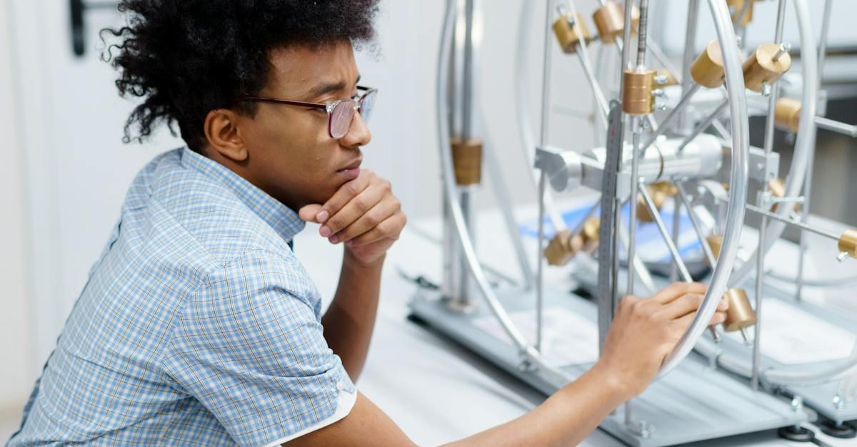 a man wearing glasses is looking at a model of a molecule in a lab .