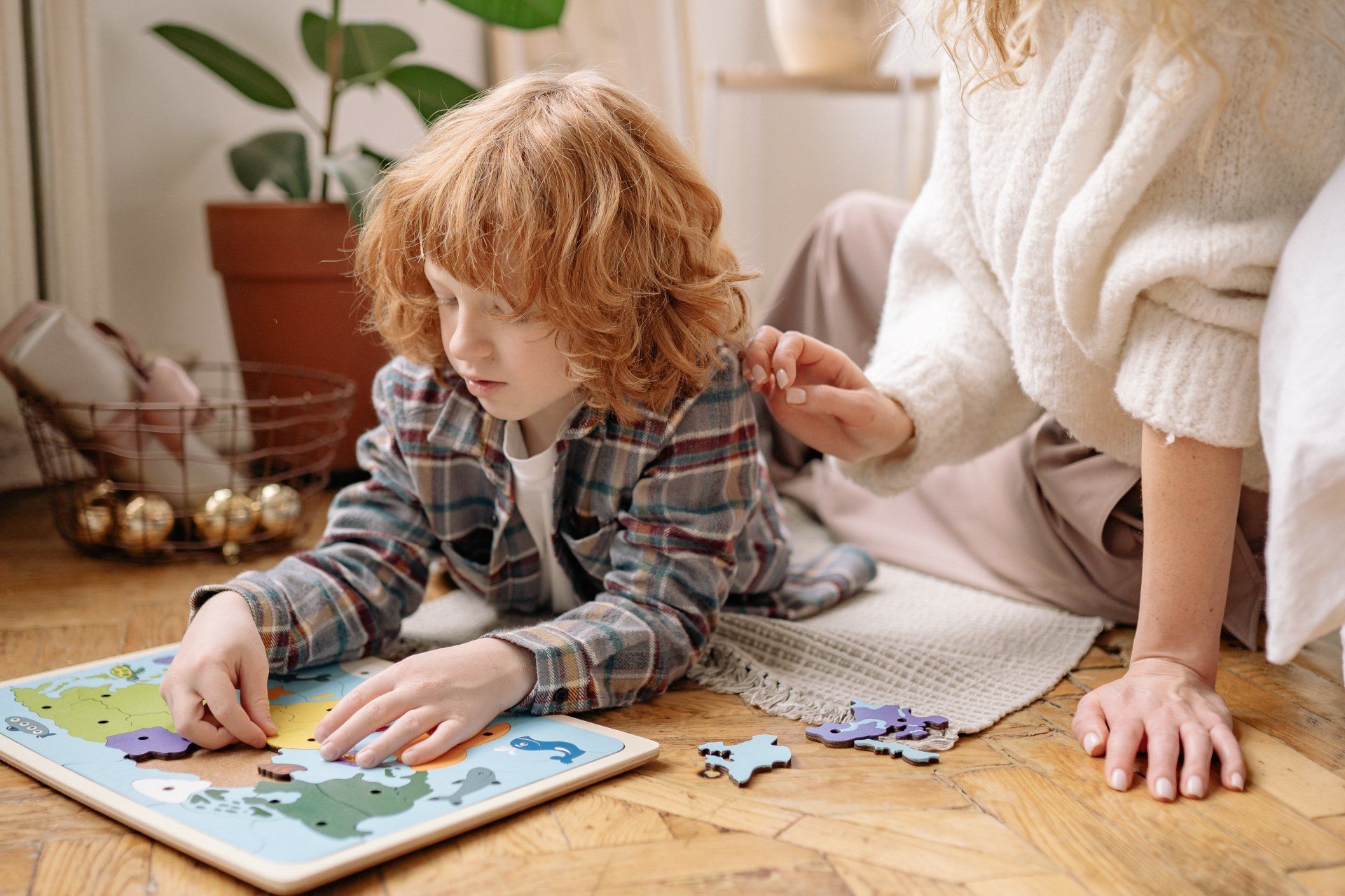 A woman and a child are playing with a puzzle on the floor.