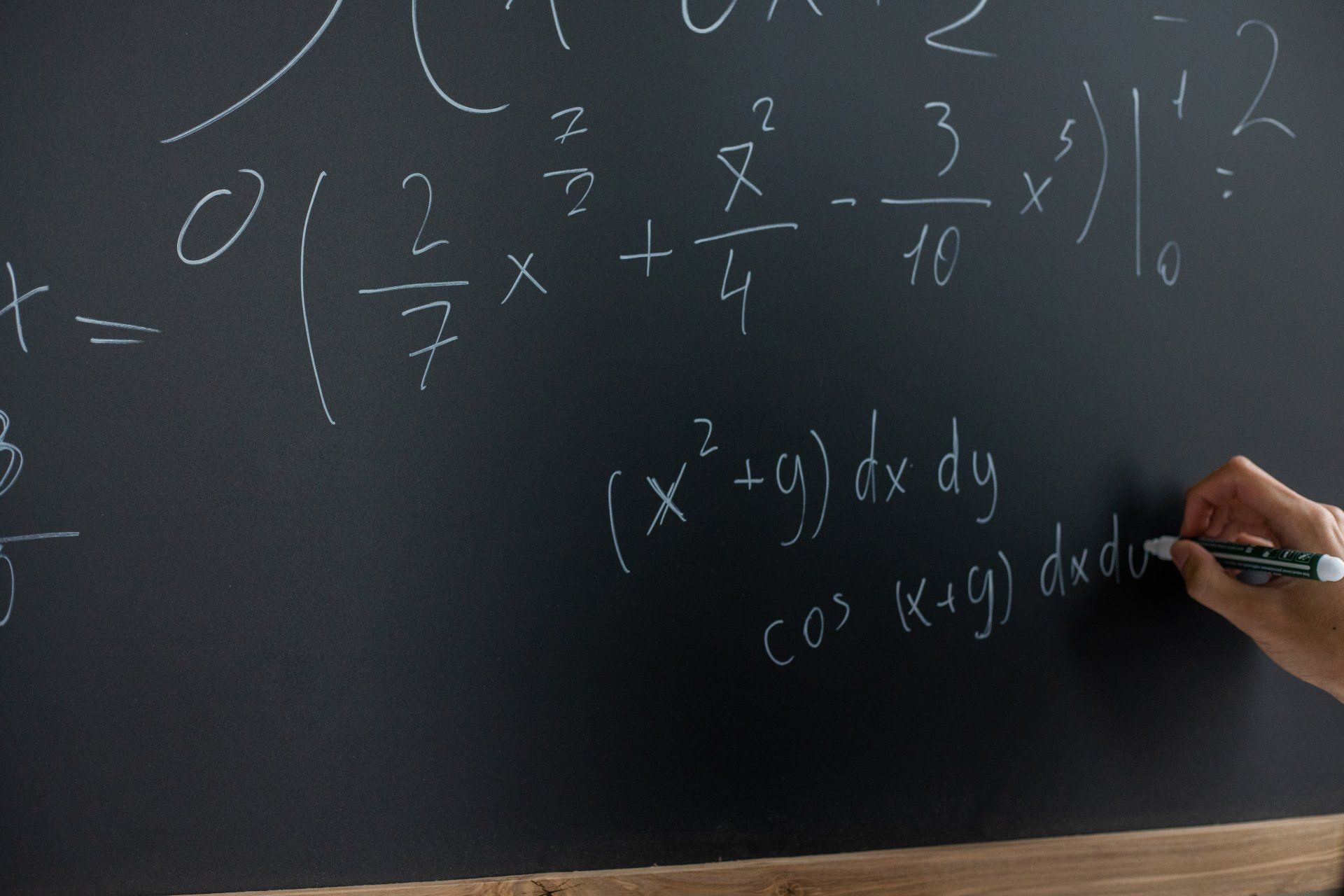 A person is writing on a blackboard with a marker.