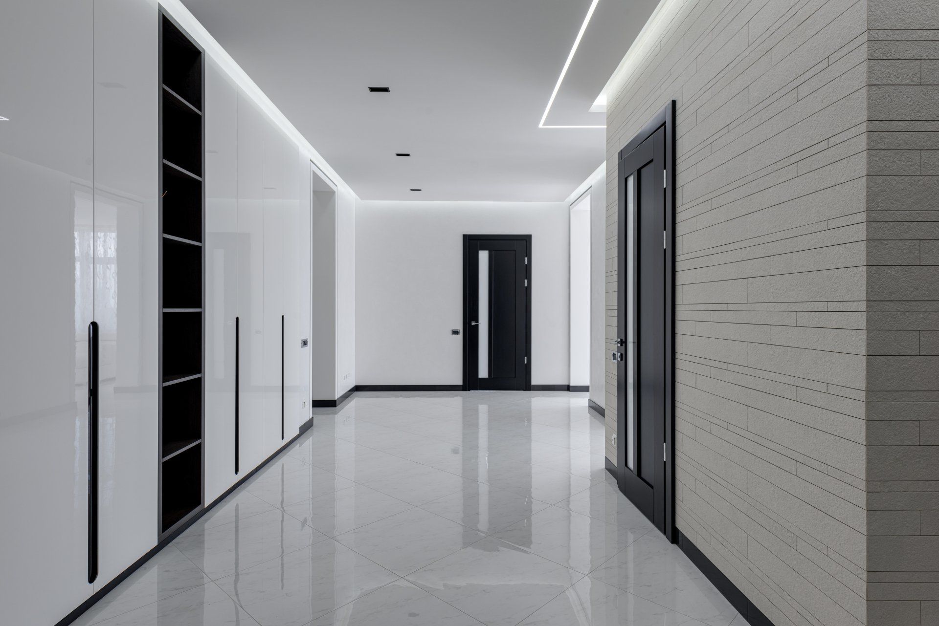 An empty hallway with white walls and a black door.