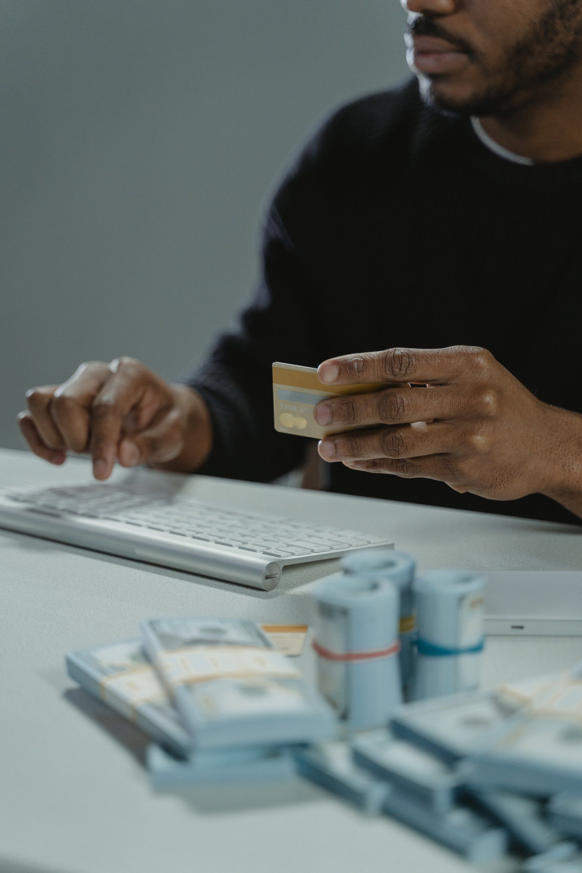 A man is sitting at a table holding a credit card and a keyboard.