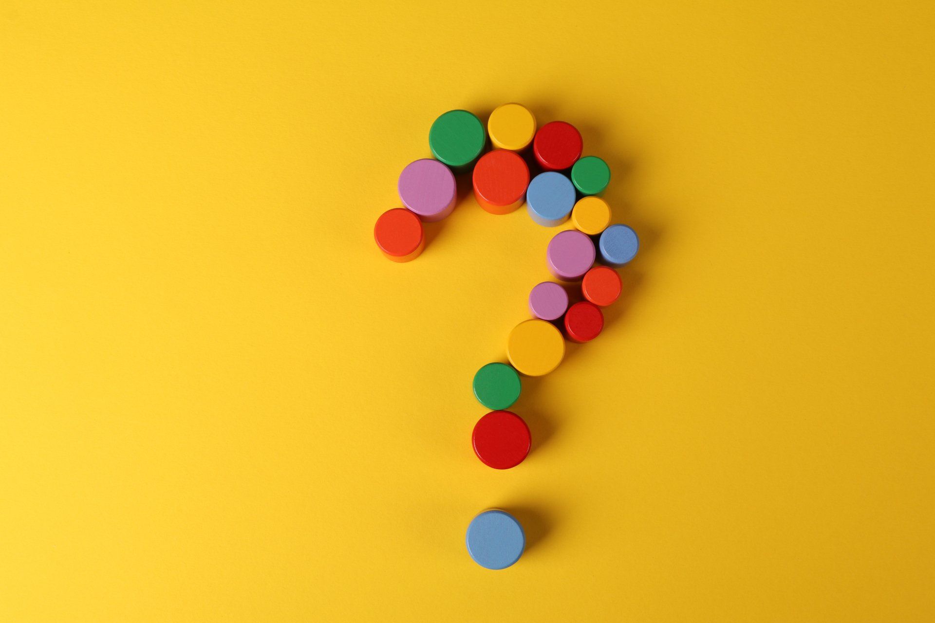 a question mark made of colorful circles on a gold background.