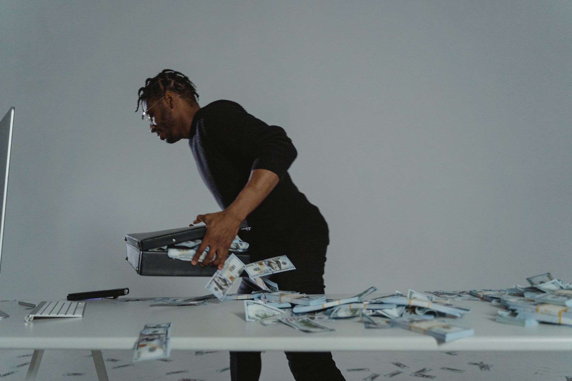 A man stealing a lock/safe box from a plastic table with the box spilling money