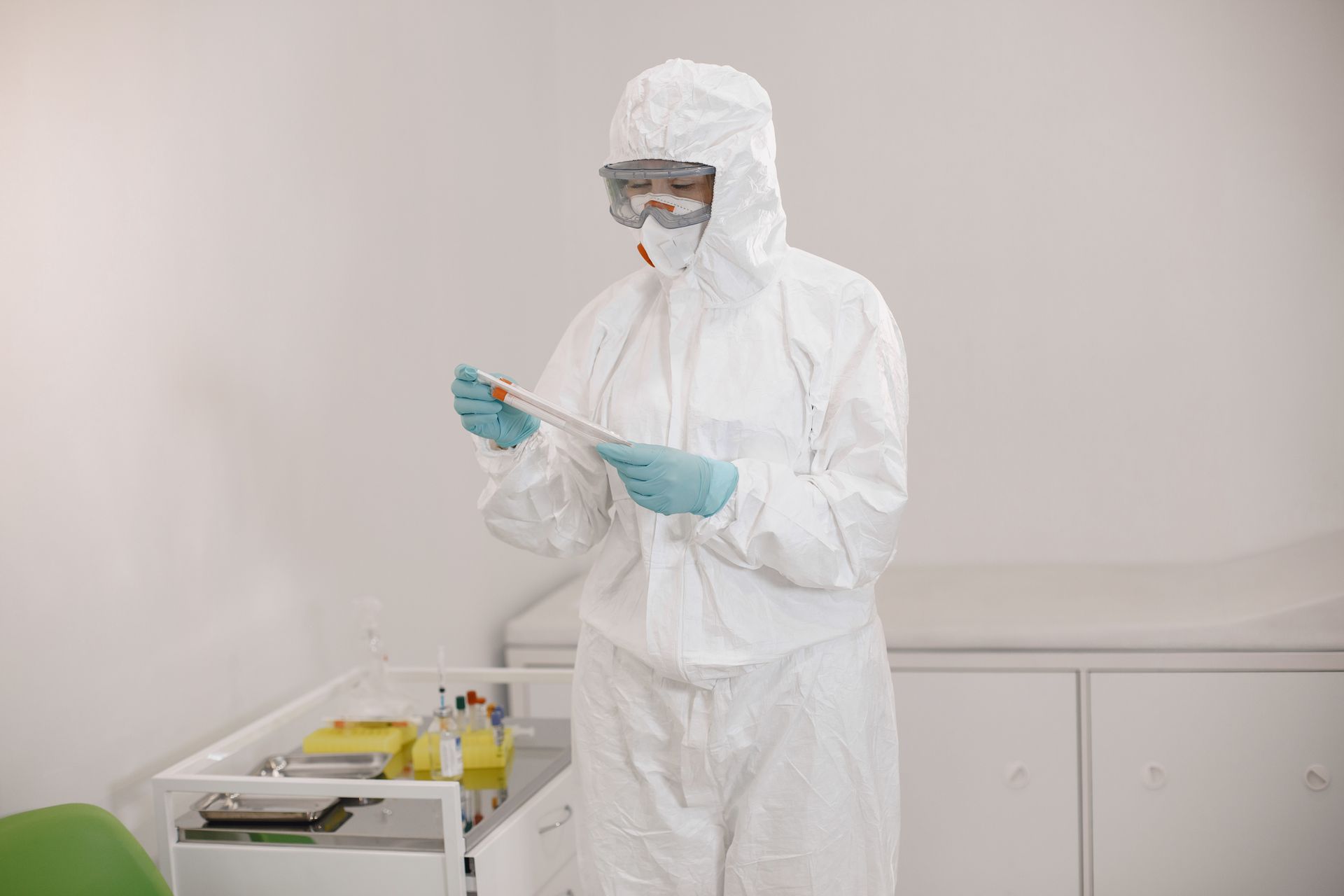 A doctor in a protective suit is looking at a piece of paper.