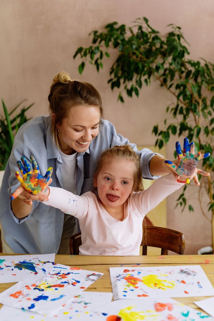 A picture of a young child happy with paint on her hands after doing activities with her support worker