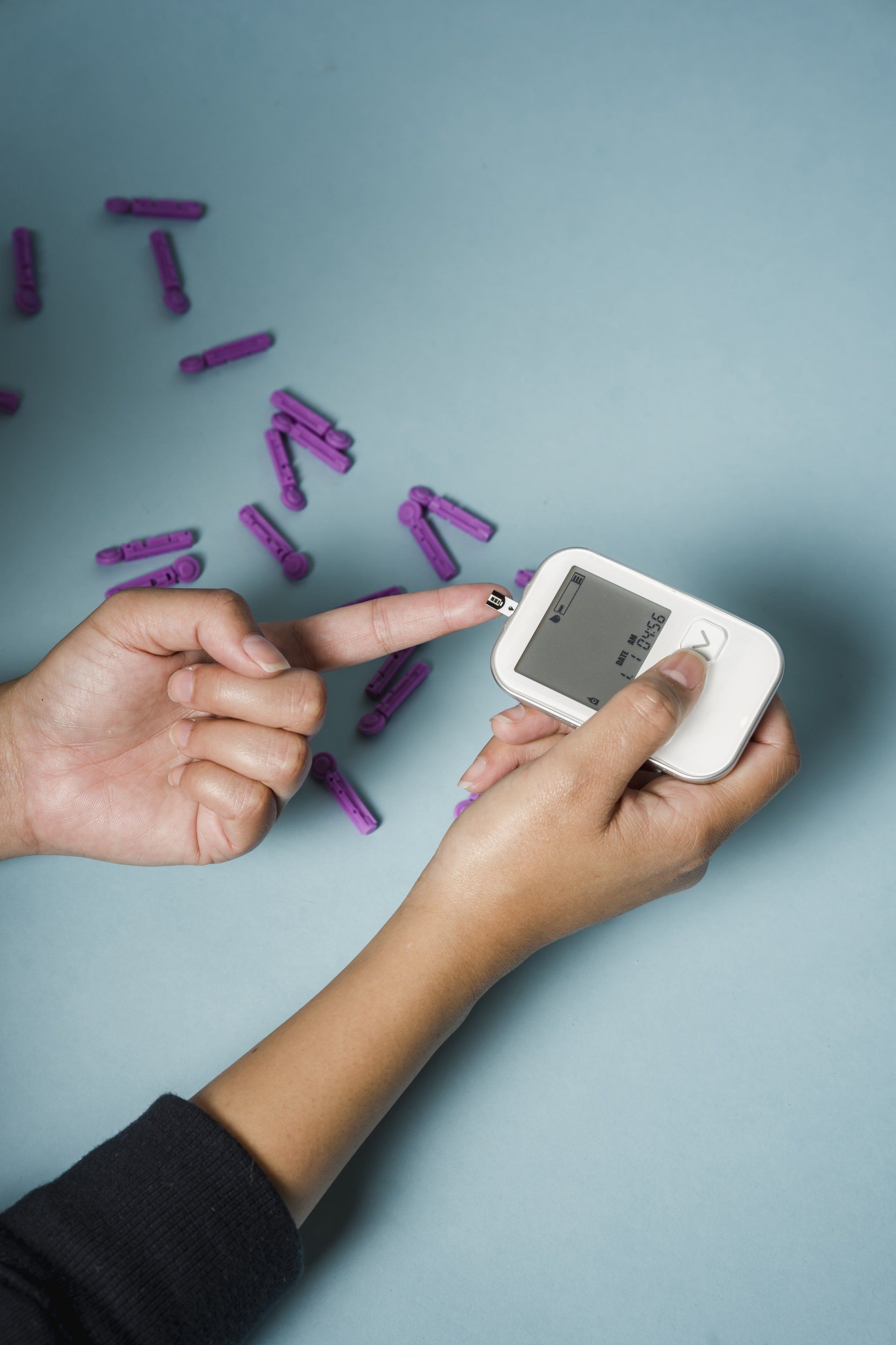 a glucose meter being pressed agains the hand of a diabetic.