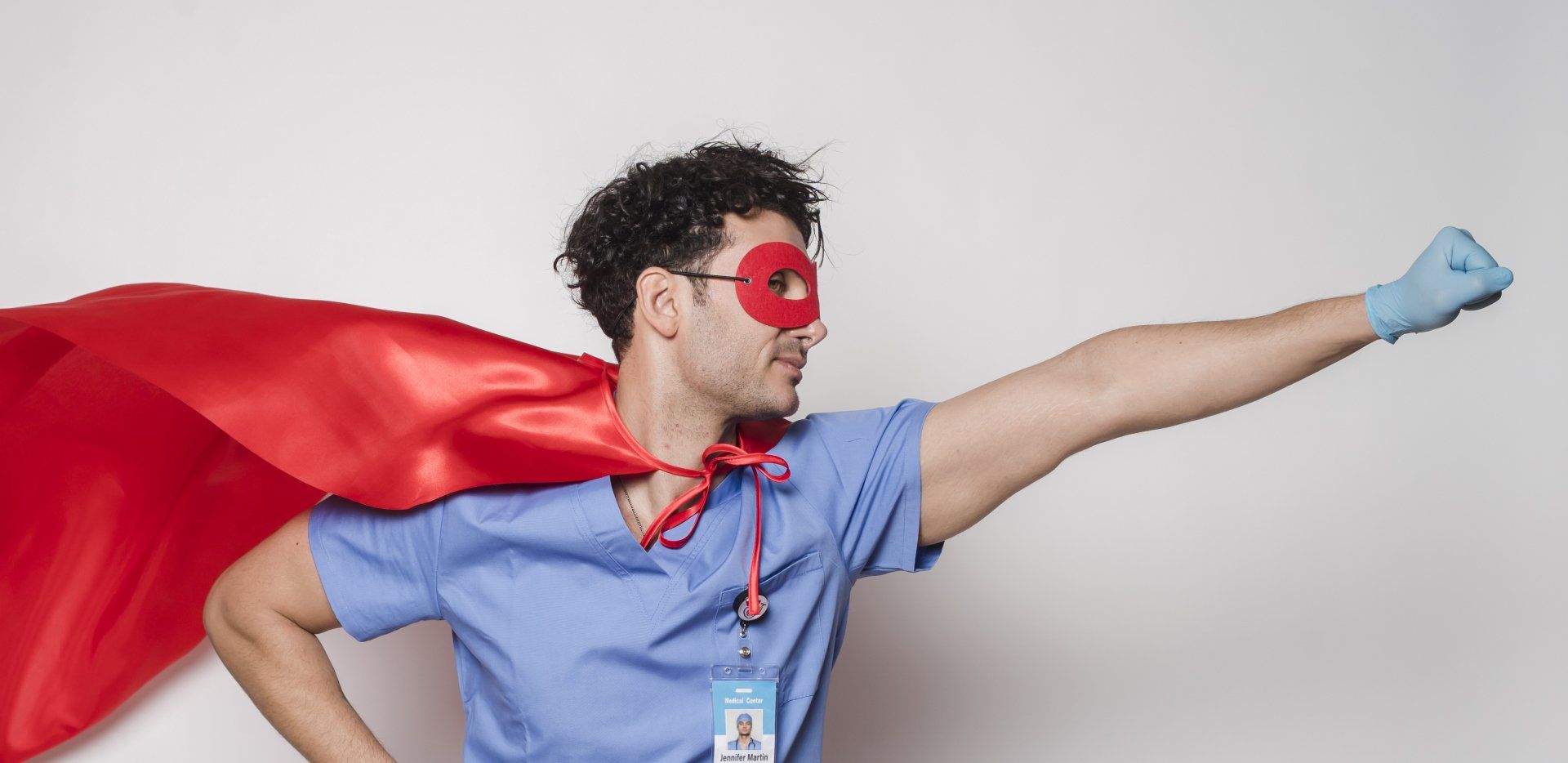 A doctor is dressed as a superhero with a red cape and mask.