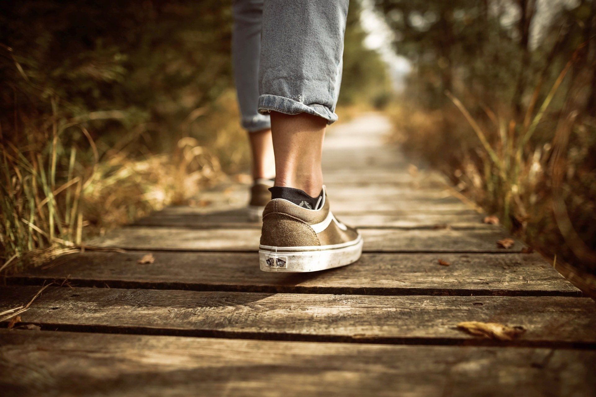 A person is walking across a wooden bridge.