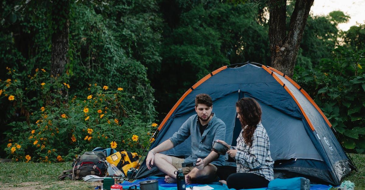 a man and a woman are sitting in a tent in the woods .
