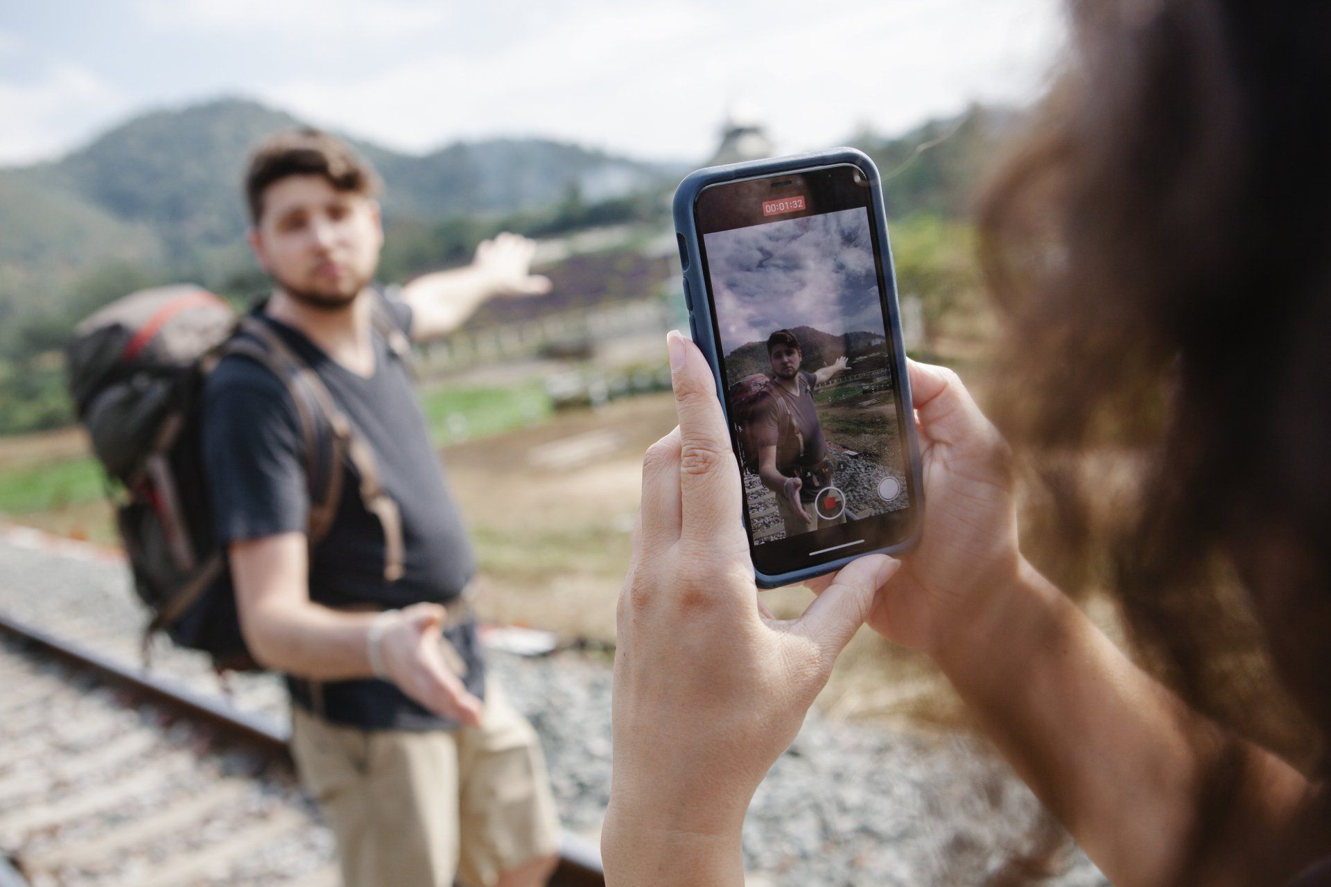 A woman is taking a picture of a man with a backpack.