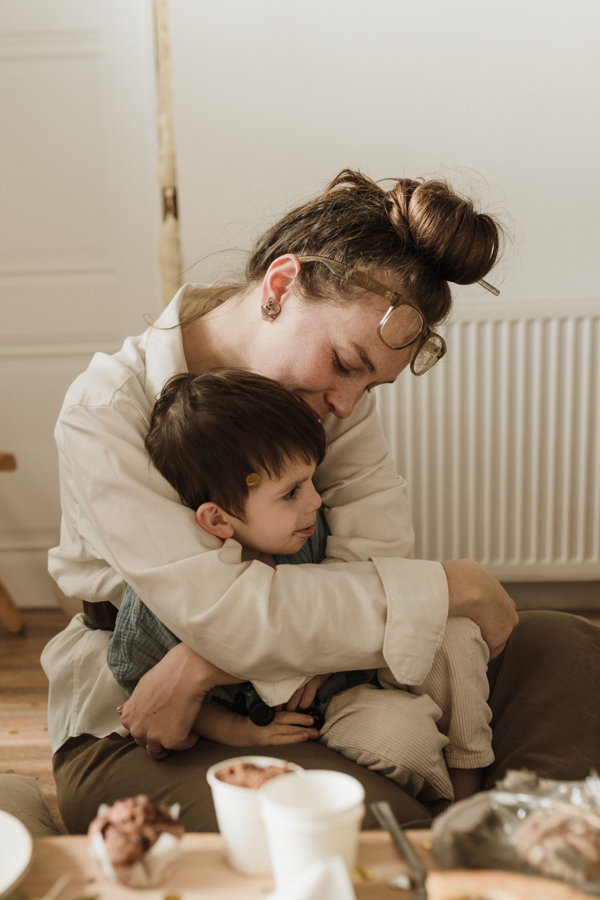 A woman is holding a child in her arms while sitting on the floor.
