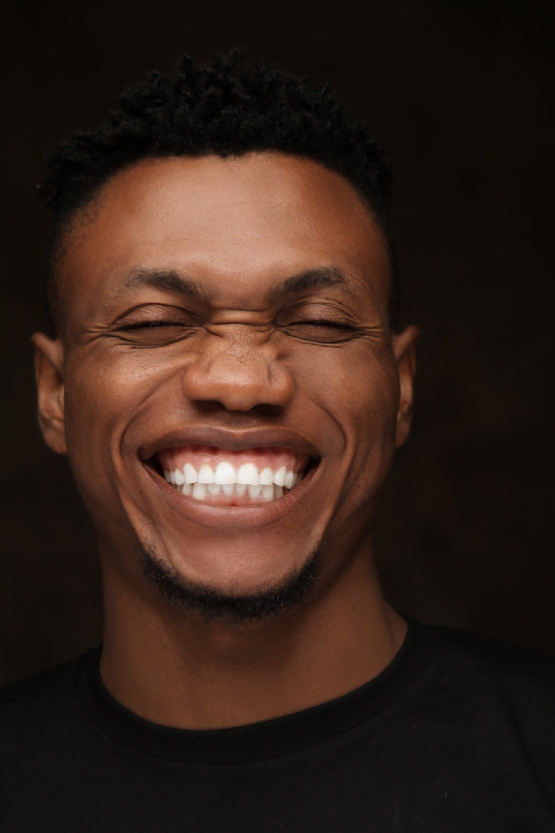 A close up of a man smiling with his eyes closed.