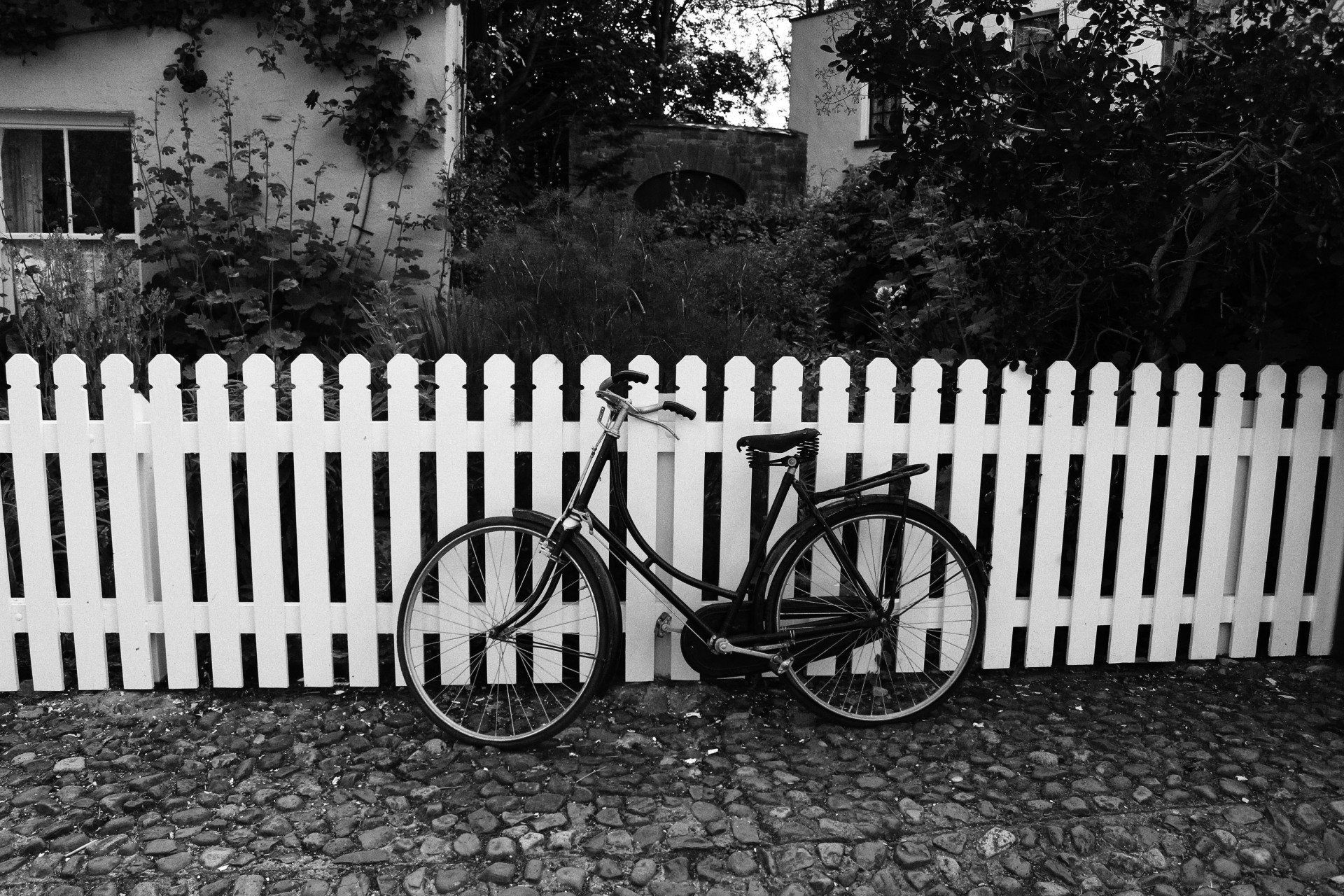 Classic wooden picket fence with an old bicycle in front with a house in back