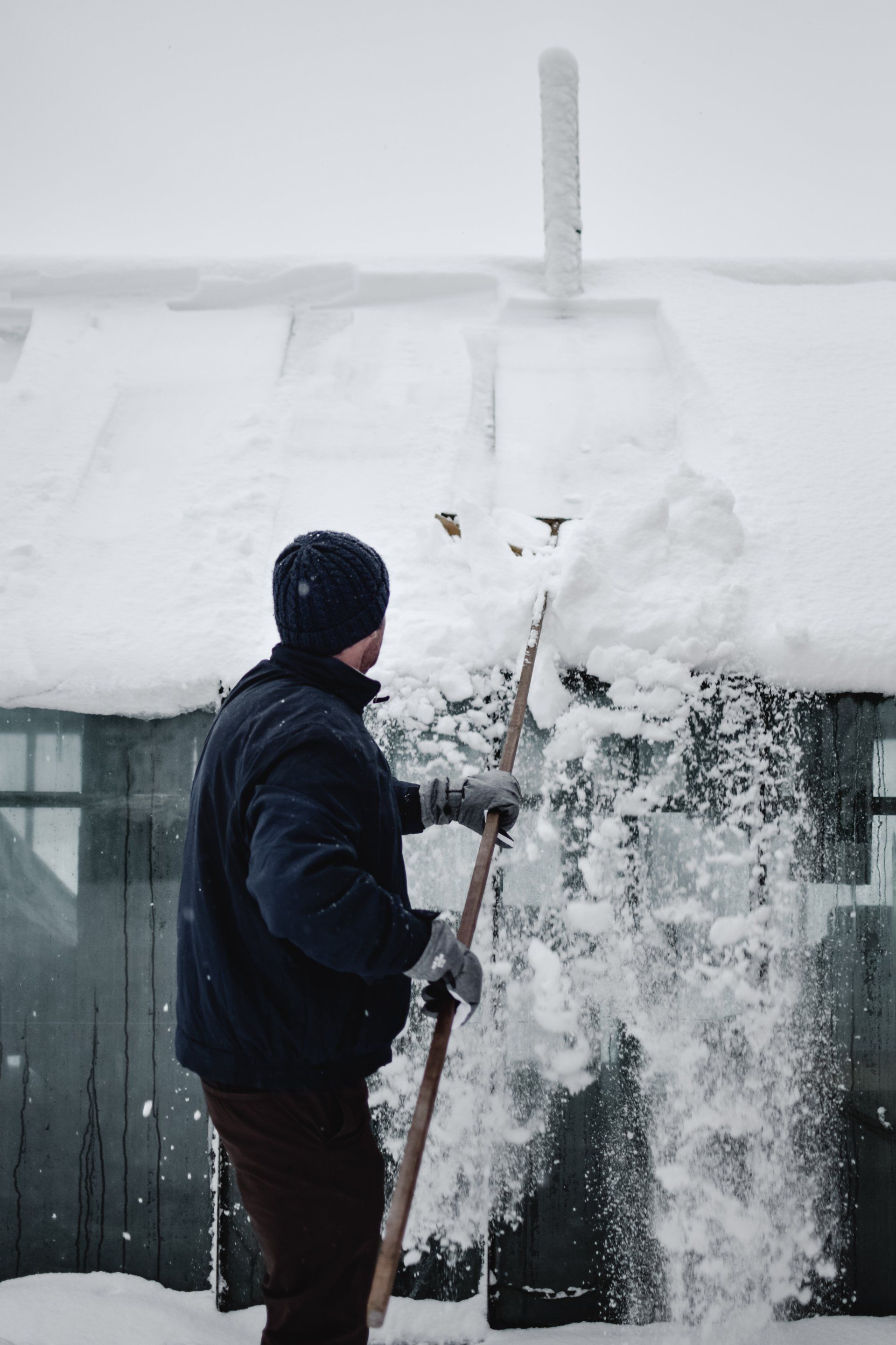 Man scraping the snow off his roof in Vermont