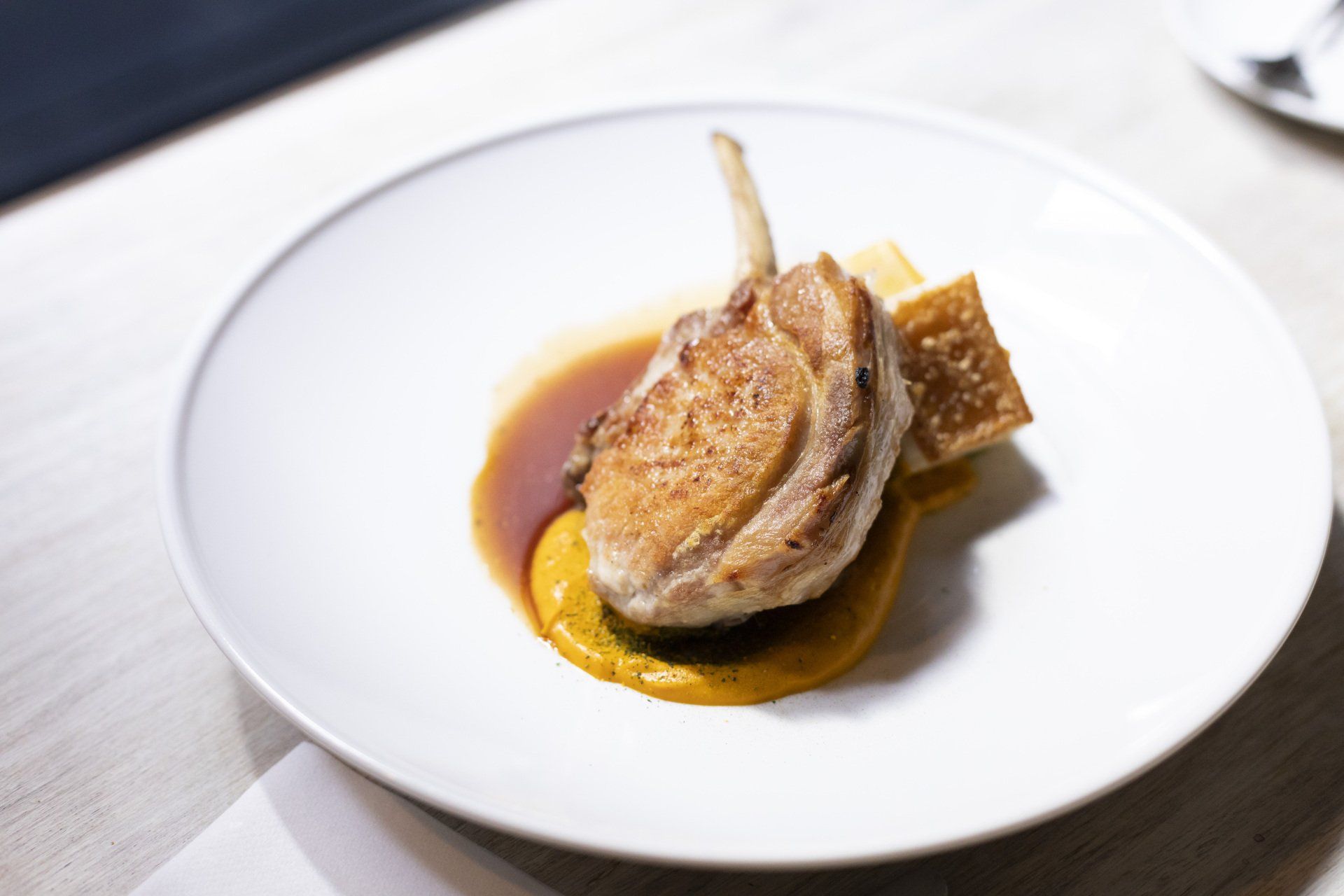 A white plate topped with meat and sauce on a table.