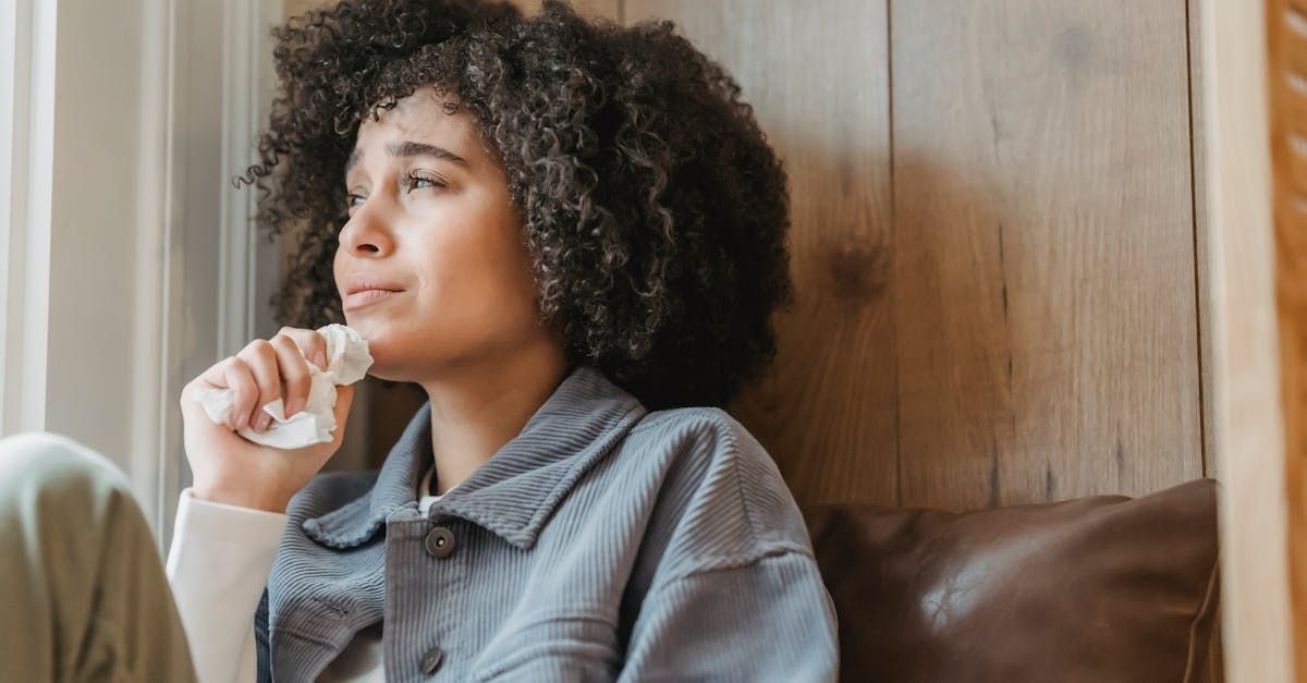 A woman is crying while sitting on a couch.