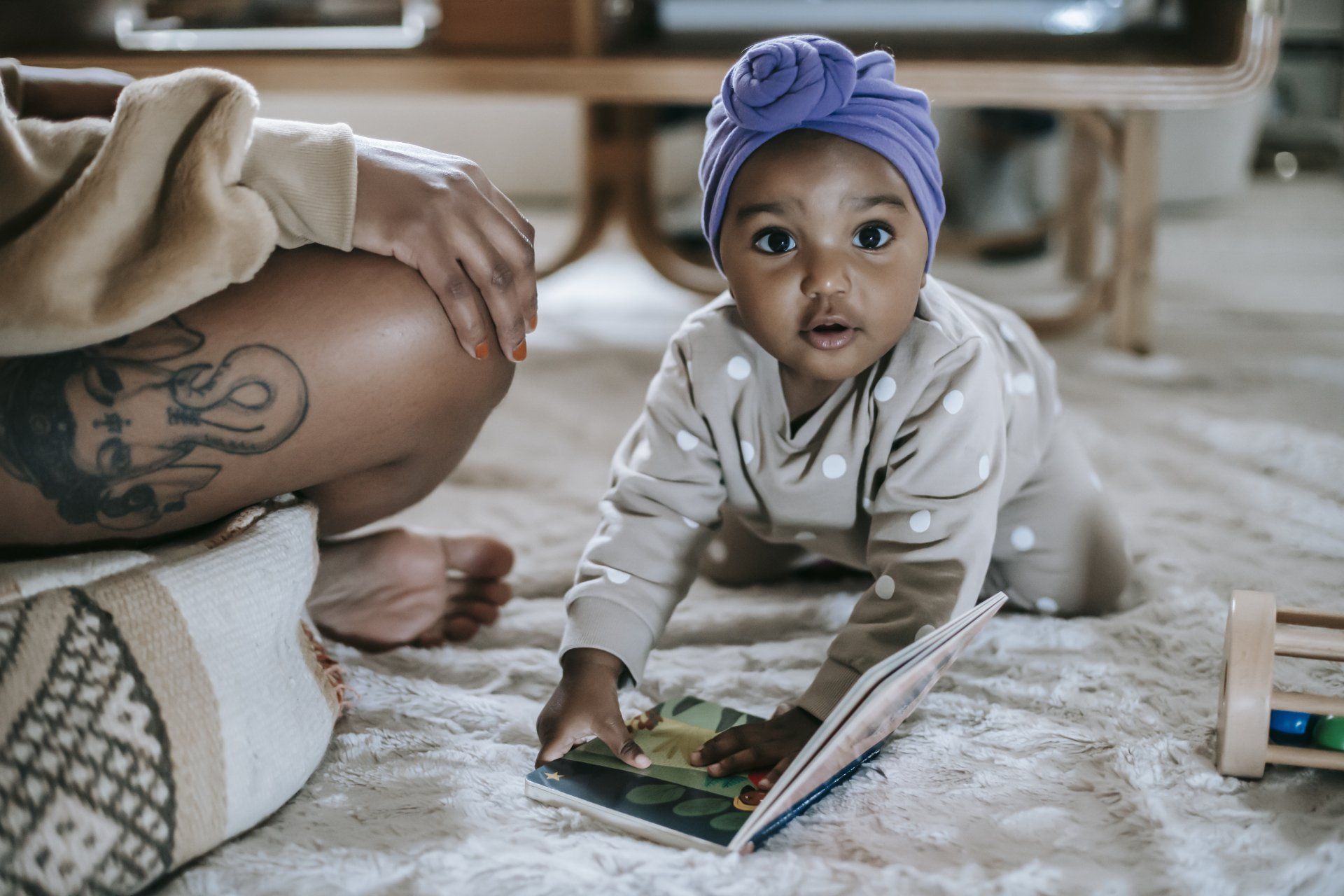 A baby is crawling on the floor while reading a book.