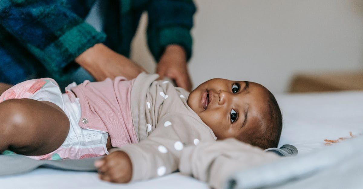 A woman is changing a baby 's diaper on a bed.