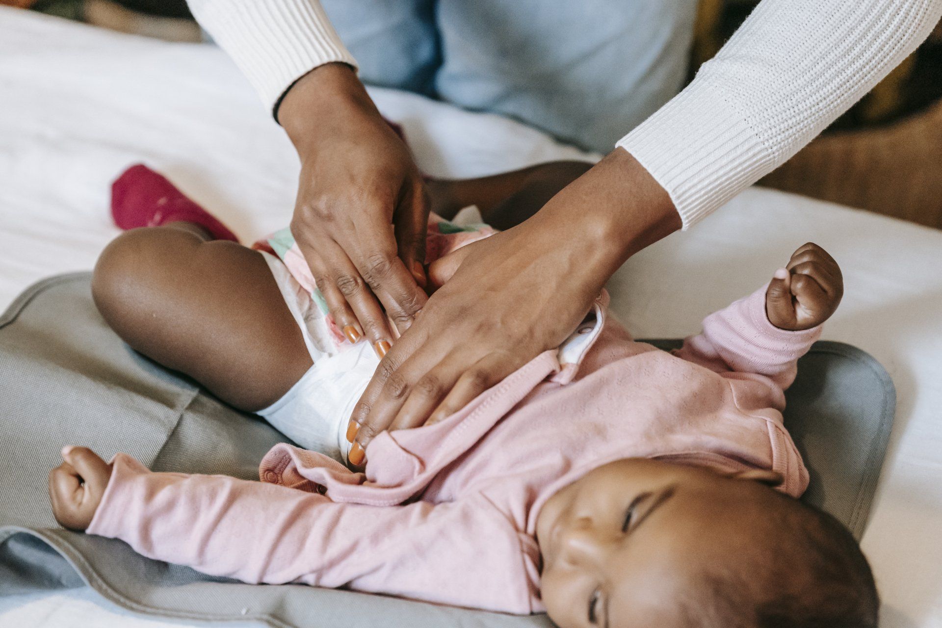 A woman is changing a baby 's diaper on a bed.