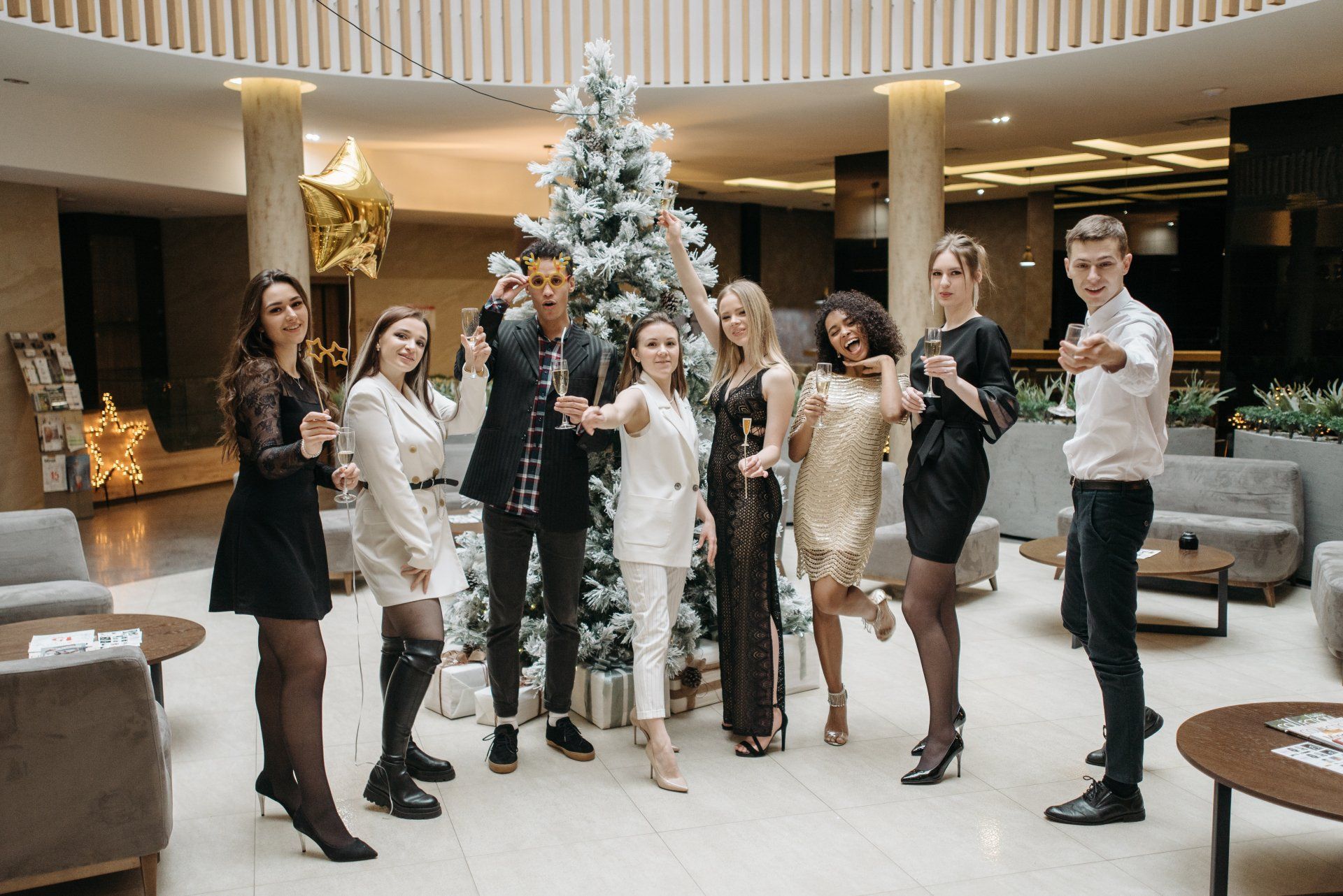 Young corporate workers dressed up, standing in front of a Christmas tree with glasses raised