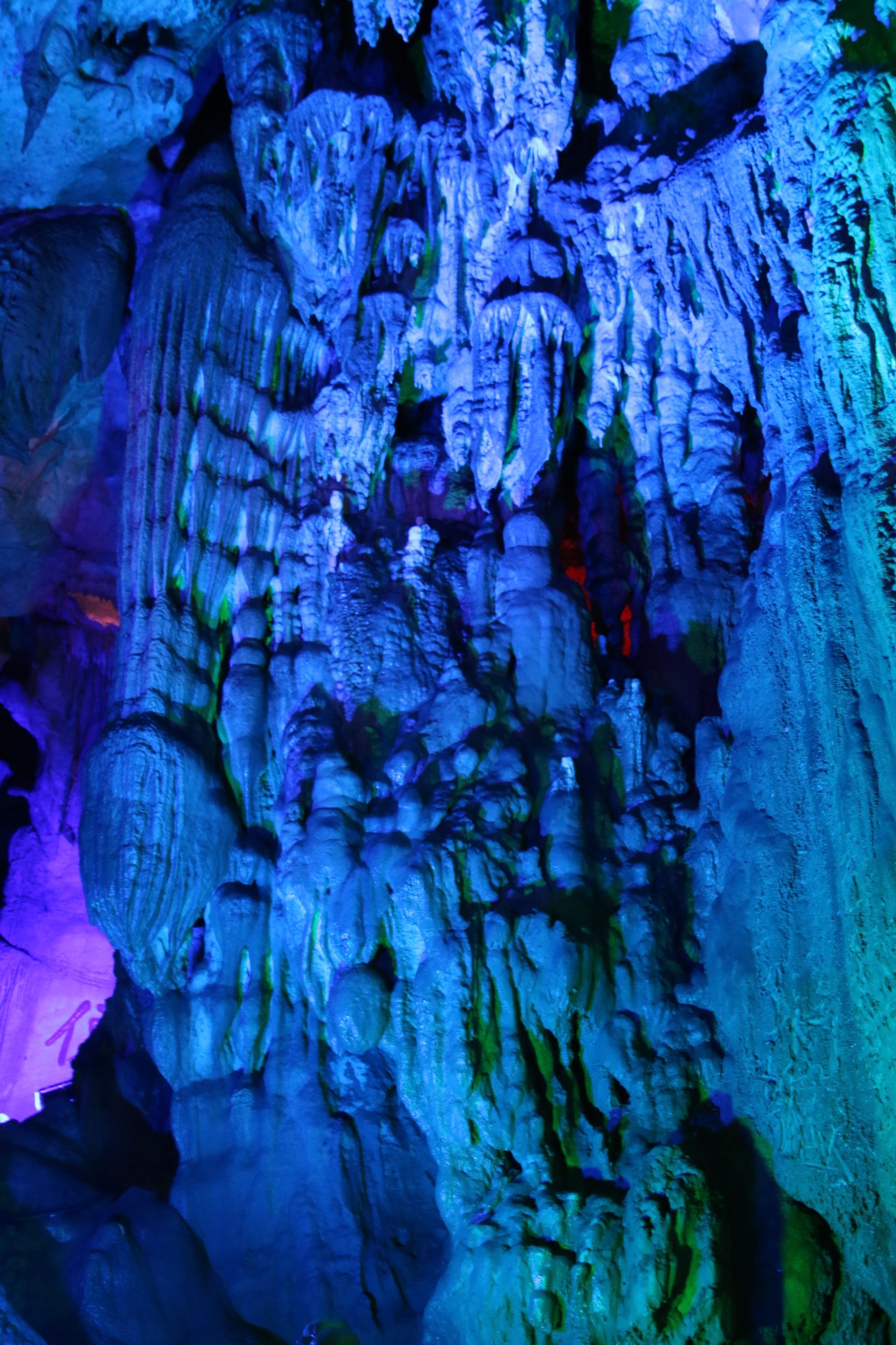 A close up of a cave with blue and green lights.