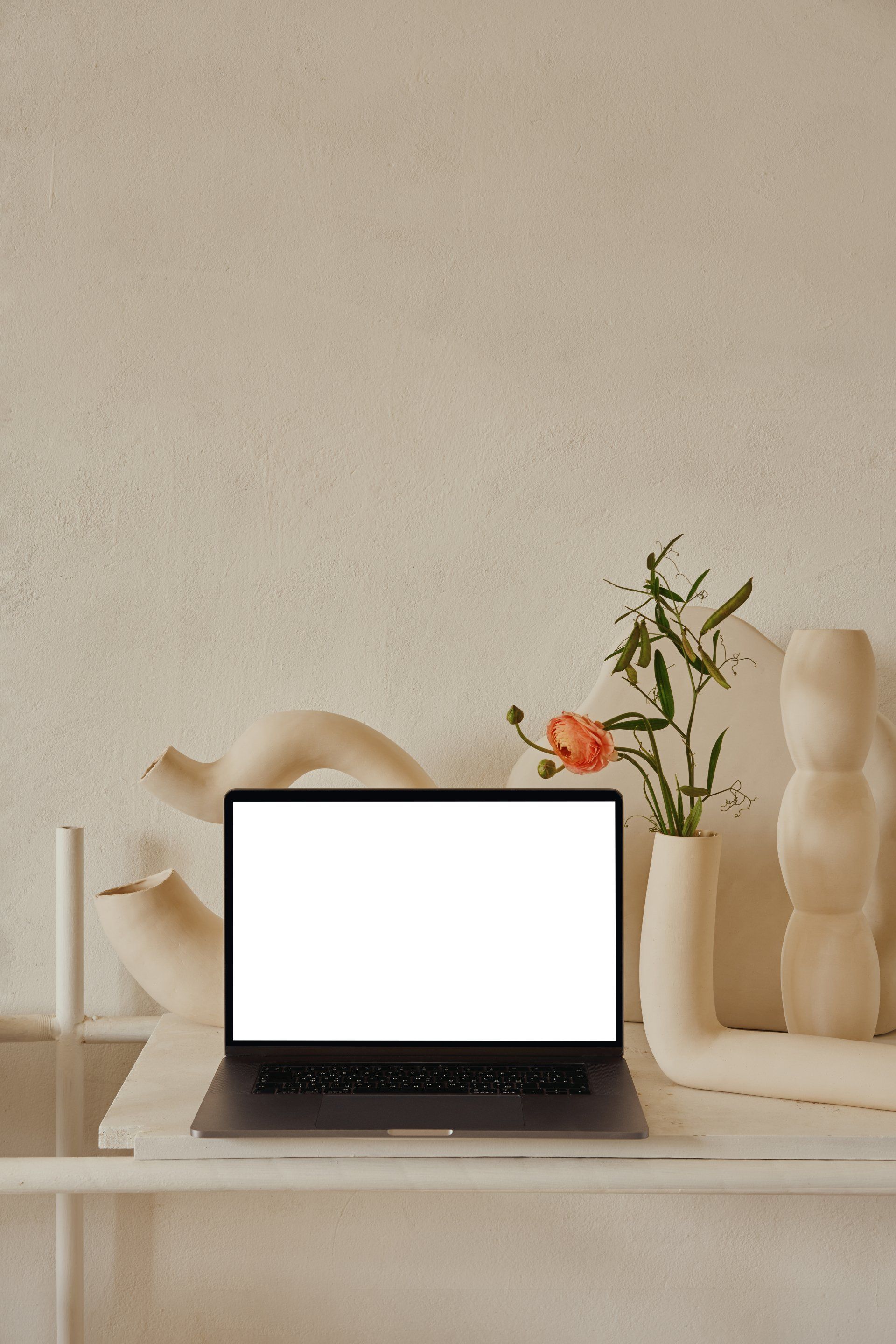 A laptop on a desk with spring flowers behind it in a vase