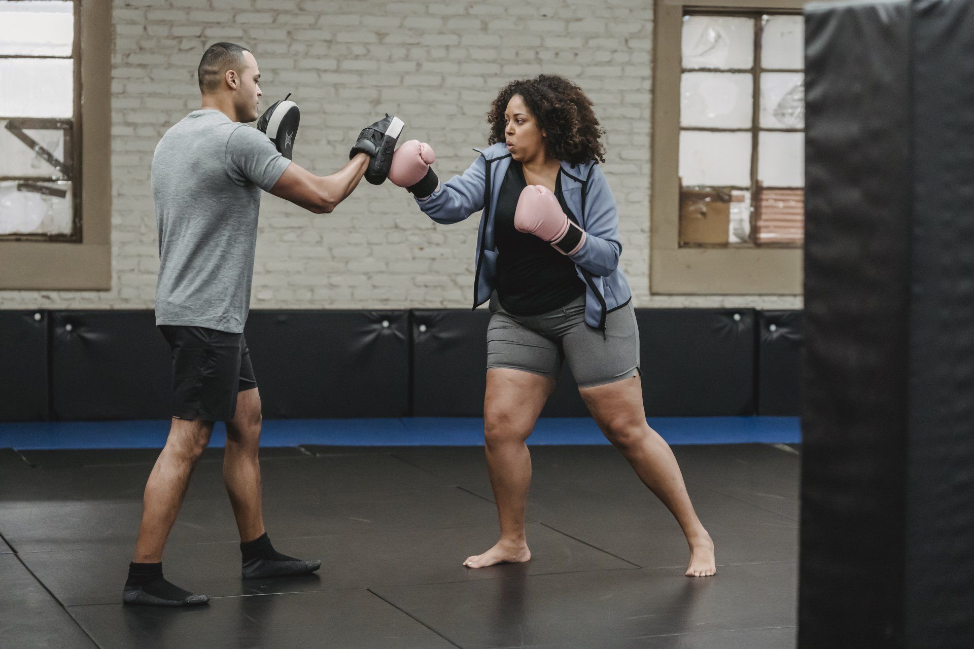 A man and a woman are boxing in a gym.