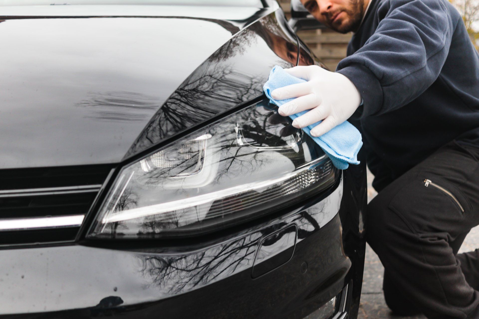 a man is cleaning the headlight of a black car with a cloth .