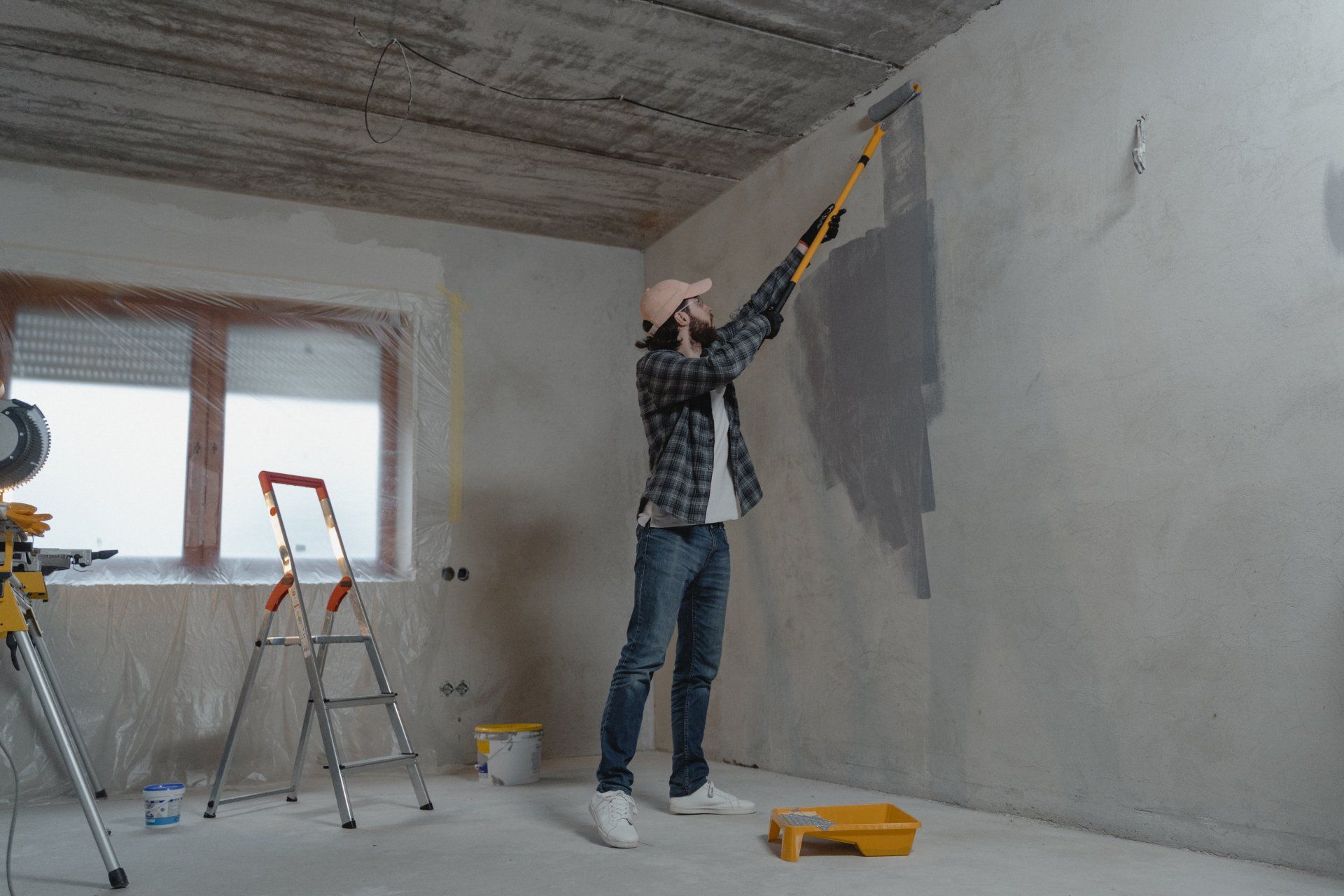 a contractor is painting a bathroom wall with a paint roller. Bathroom Gut and Remodel Cost in 2024