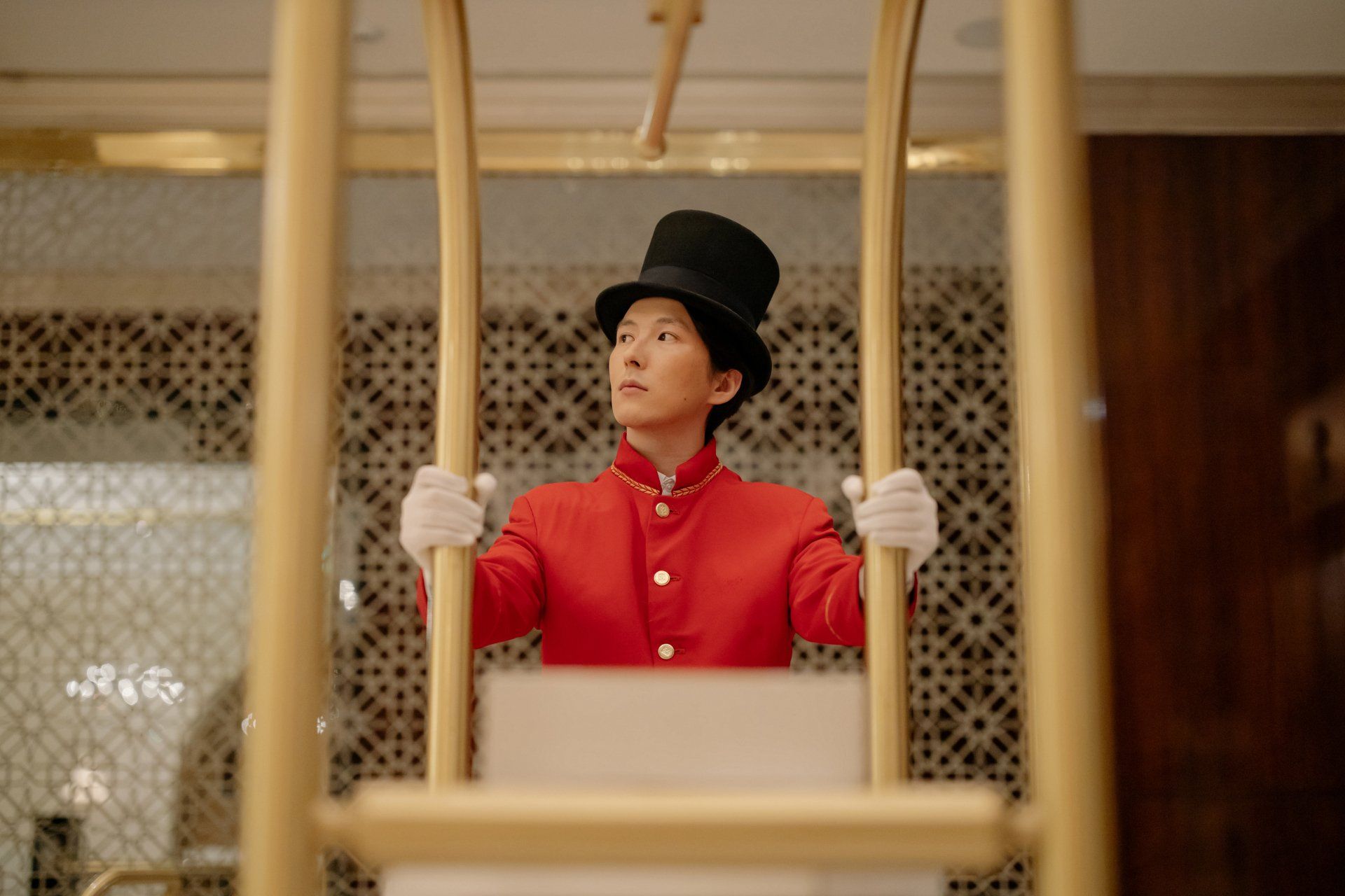 A man in a top hat is holding a ladder in a hotel room.