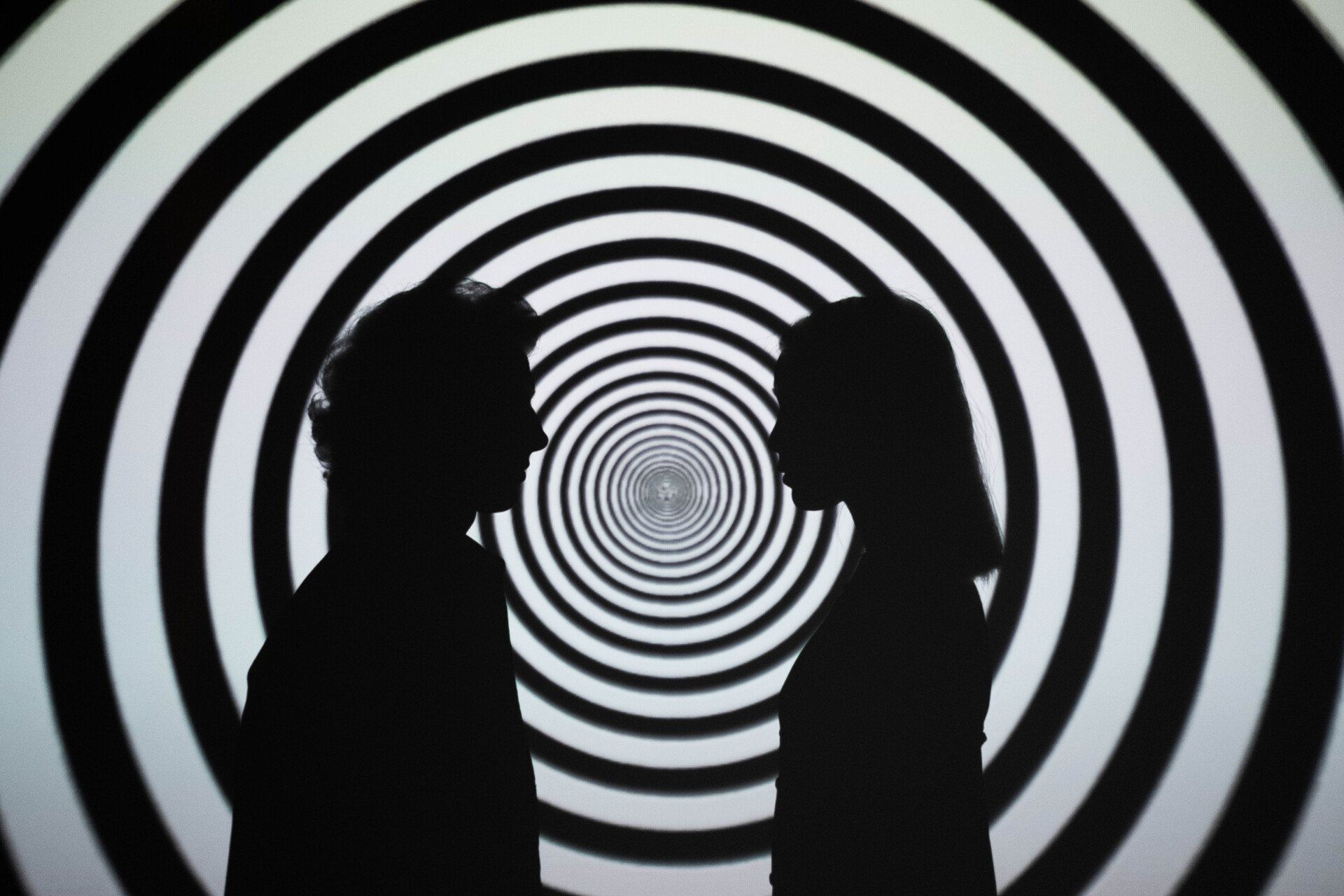 two people stand in front of optical illusion