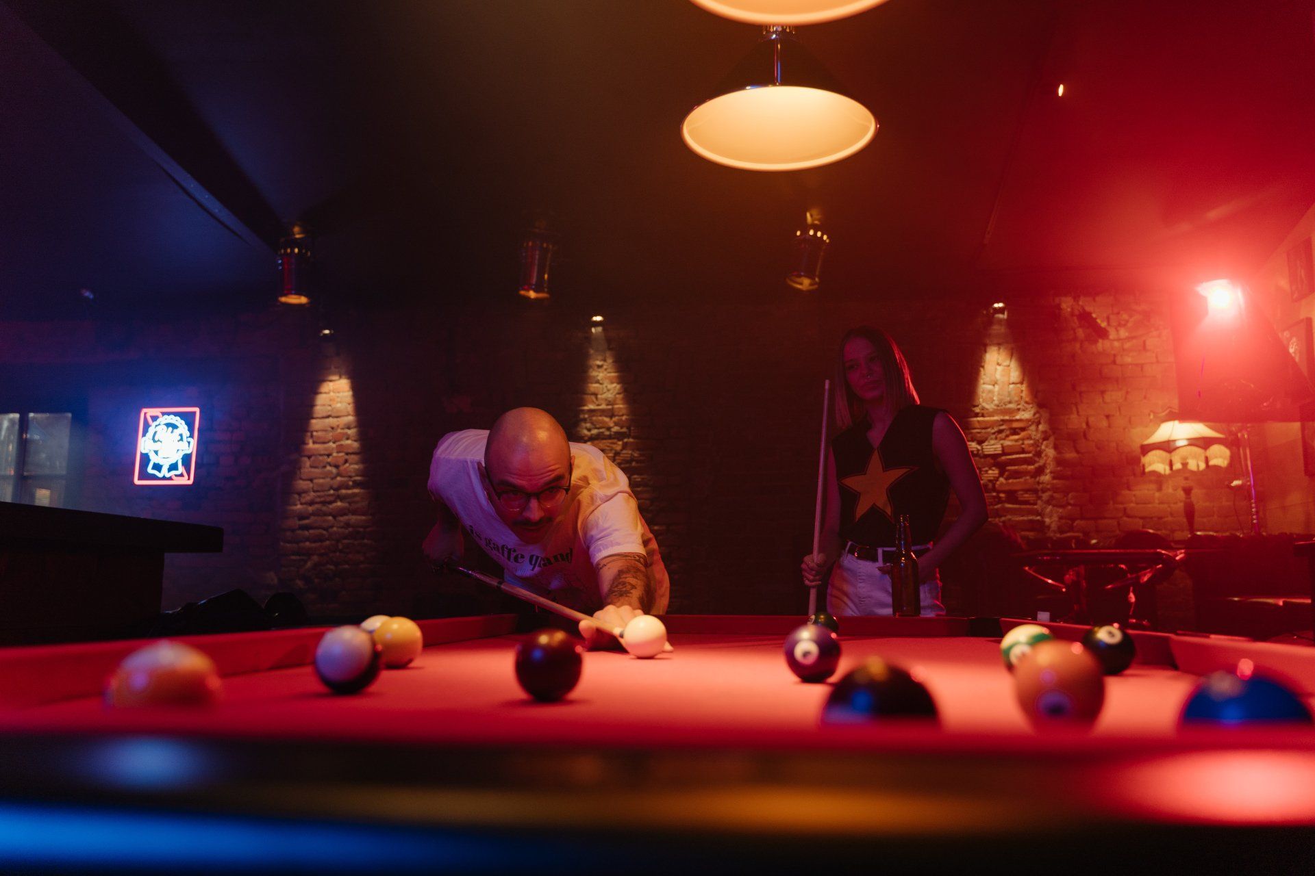 a man and a woman are playing pool in a dark room .