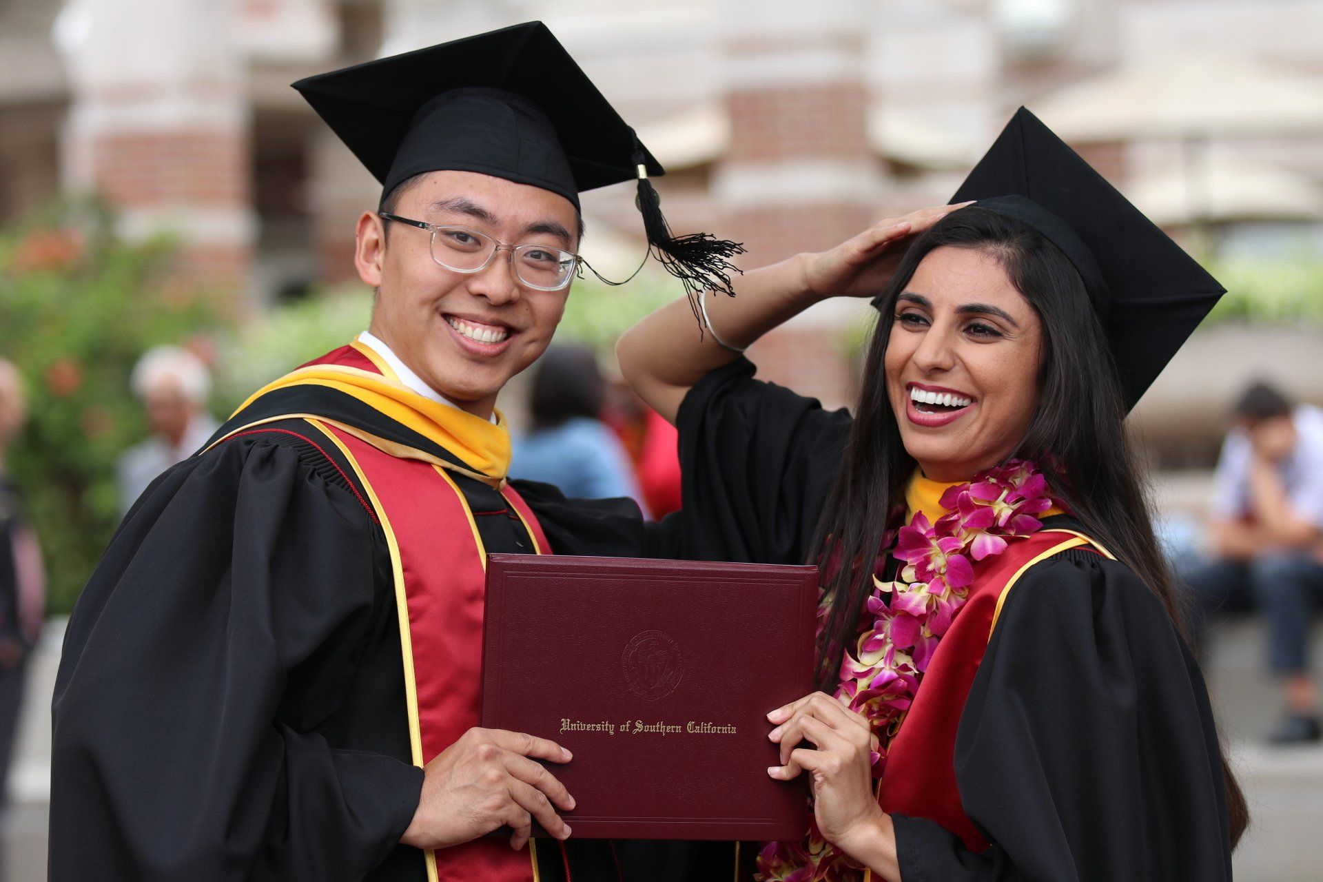 A man and a woman are posing for a picture at a graduation ceremony.