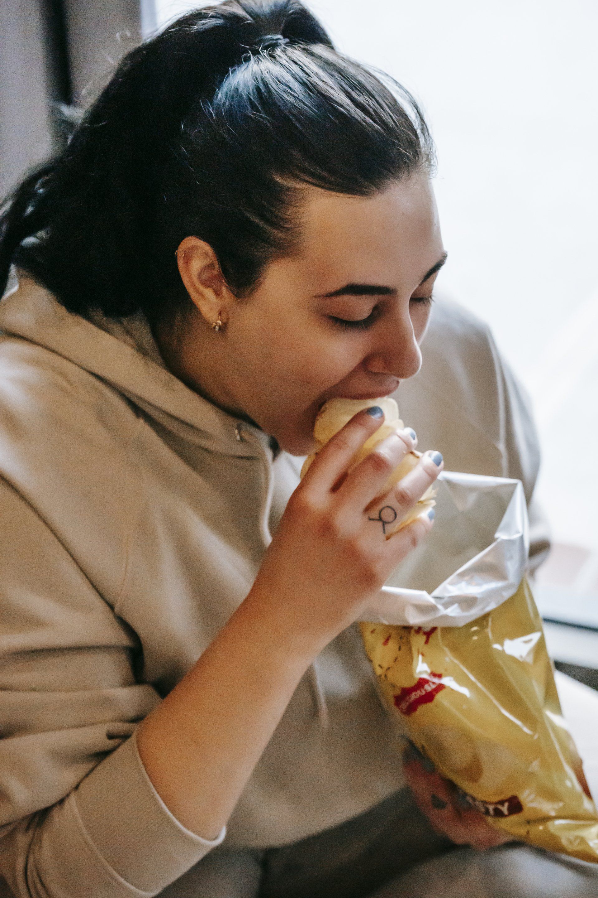 Une femme mange un sandwich dans un sac de chips.