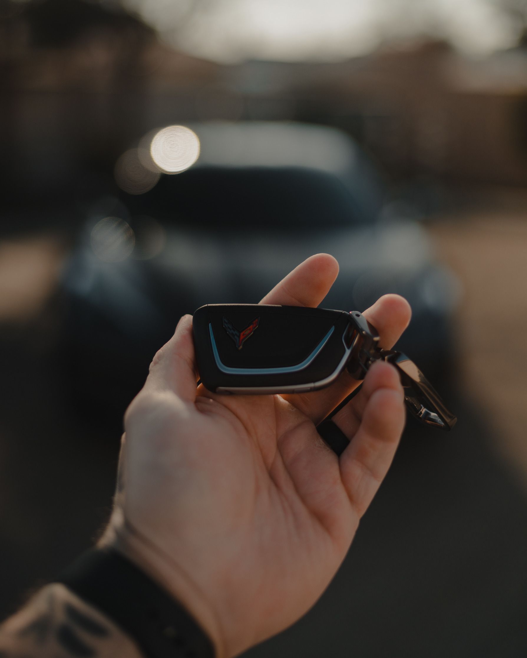 A person is holding a car key in front of a car