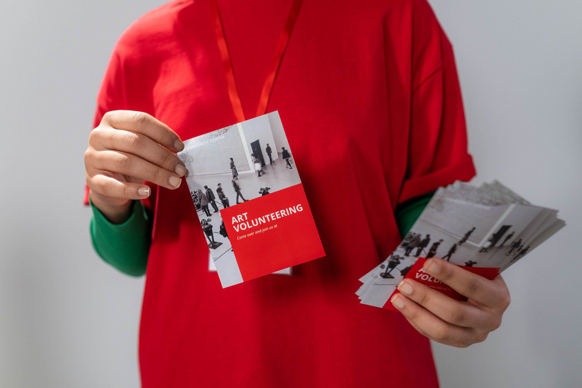 a person in a red shirt is holding a brochure in their hands .