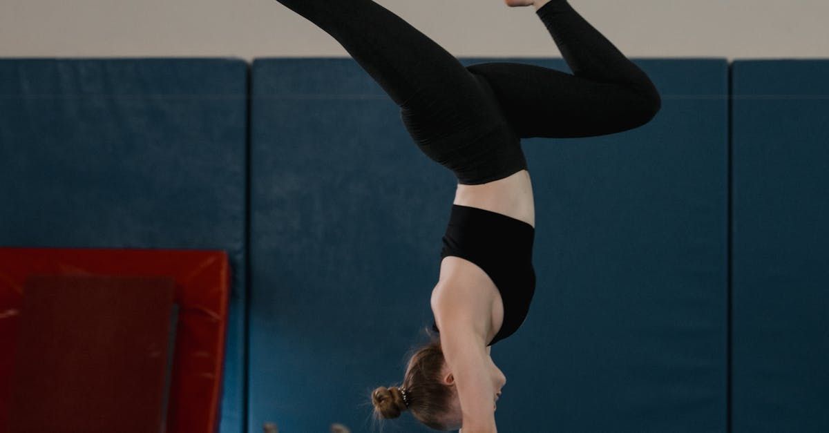 A woman is doing a handstand in a gym.