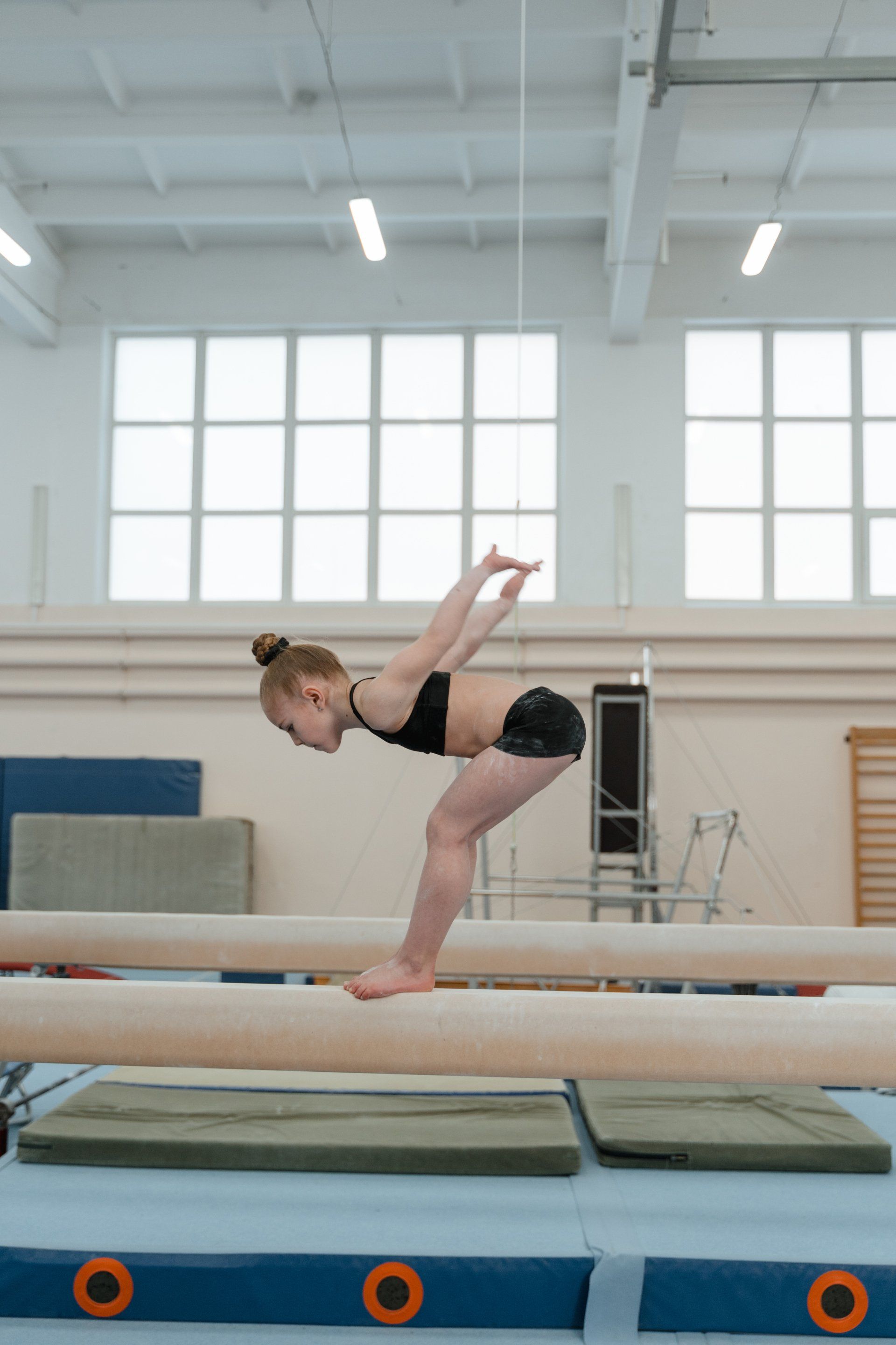 A gymnast is sitting on a balance beam covered in chalk.