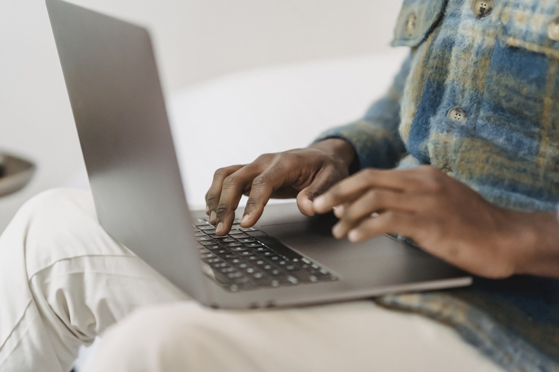 A man is sitting on a couch using a laptop computer.