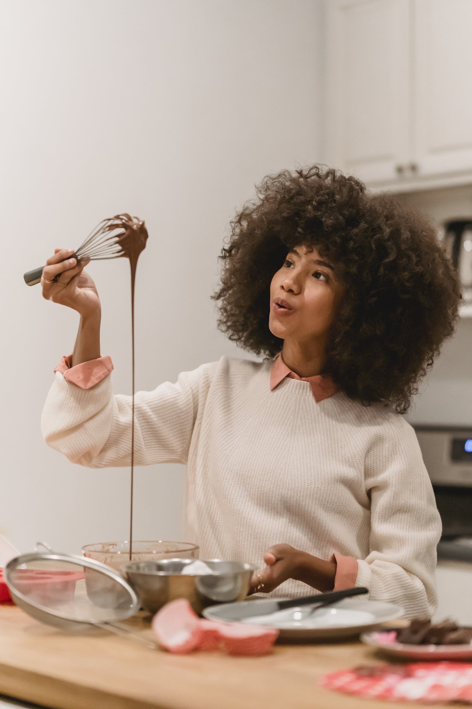 a woman is pouring chocolate into a bowl with a whisk:  Turn Your Crowded Kitchen Into A Minimalist Space