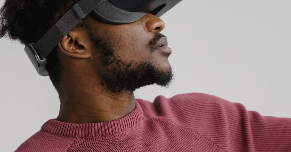 A man in a pink sweater is wearing a virtual reality headset.
