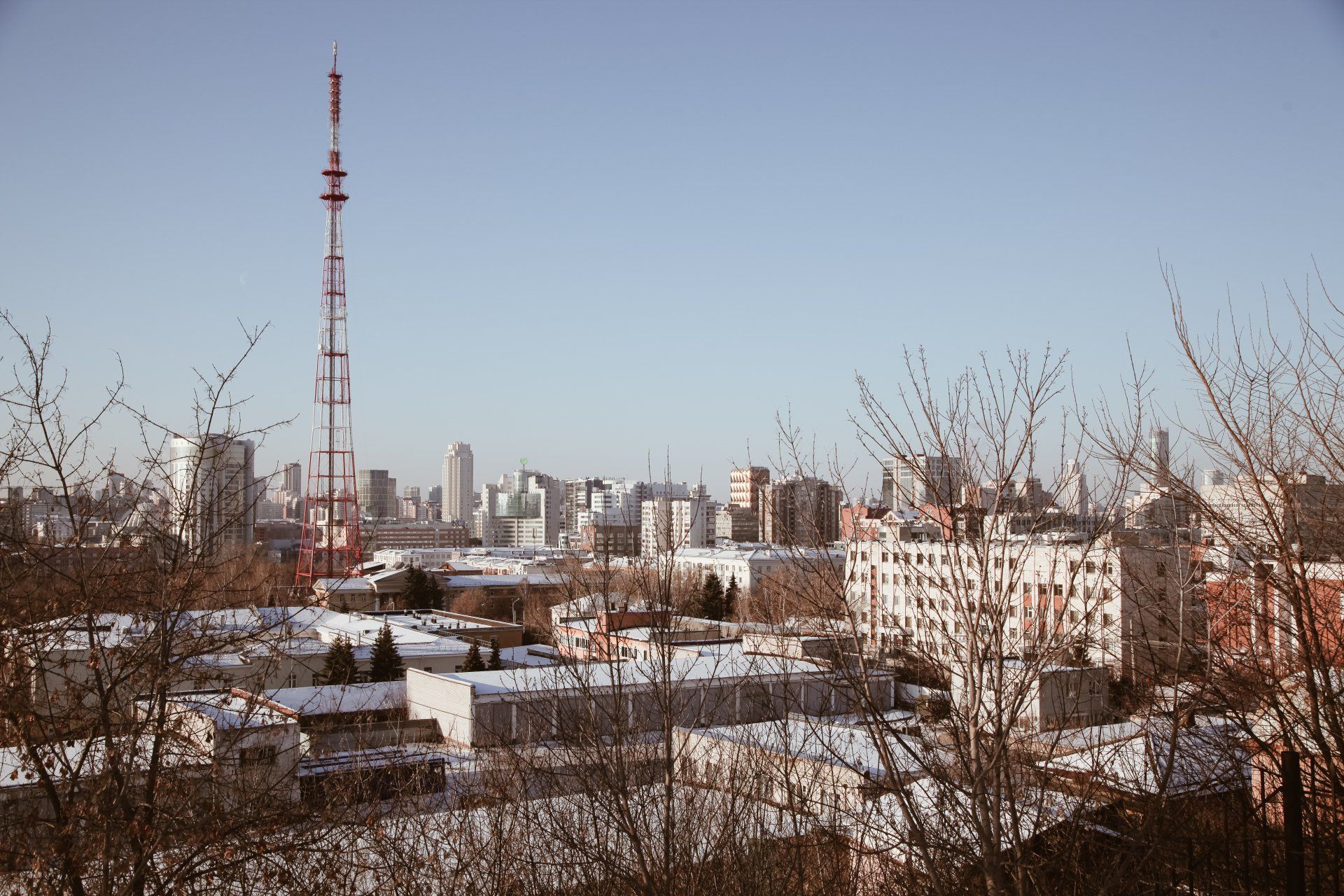 Cityscape with tall communication tower and snowy rooftops under a clear blue sky,  Reboot IT’s connected infrastructure.