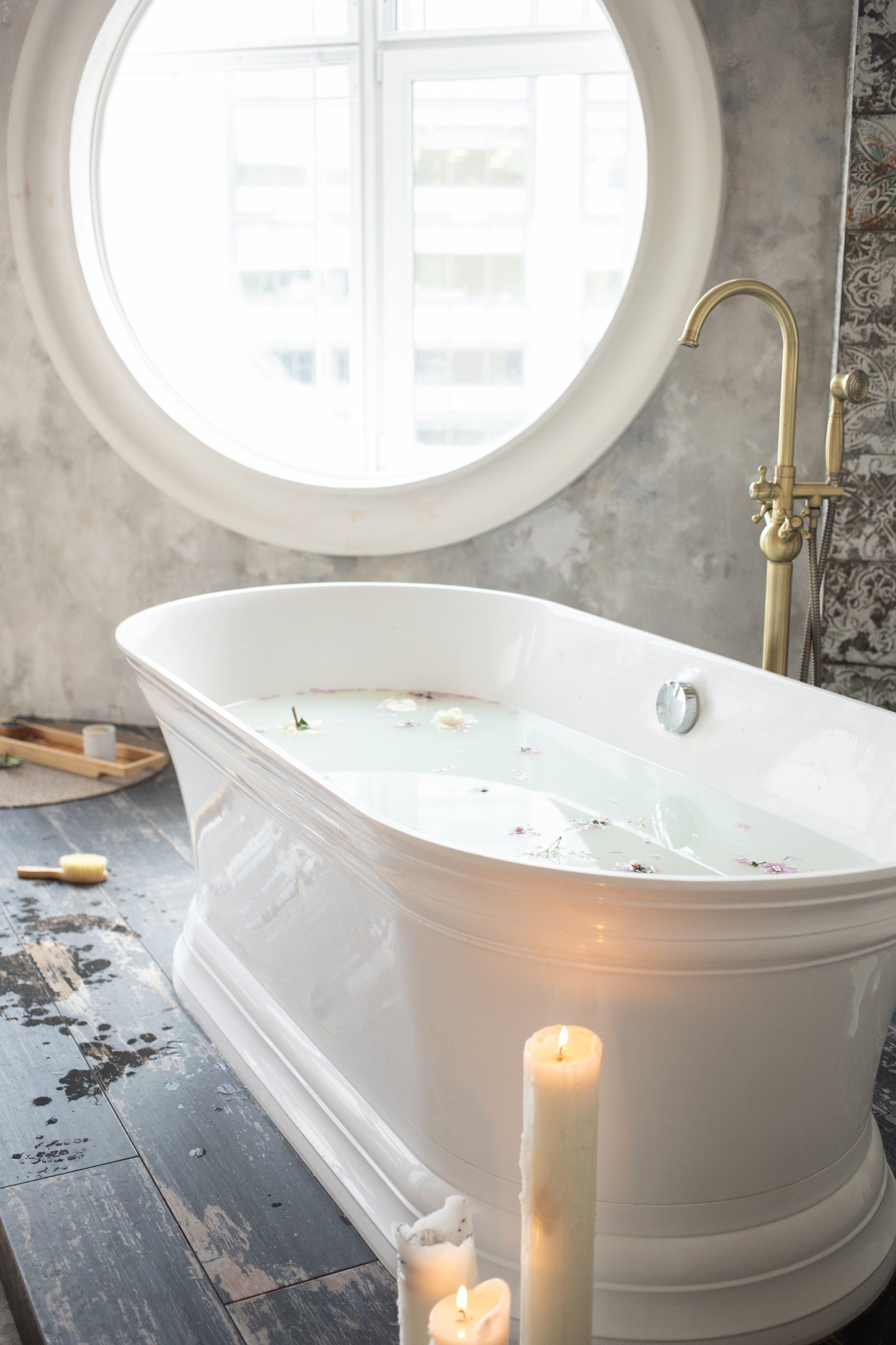 a bathtub with candles next to it and a window