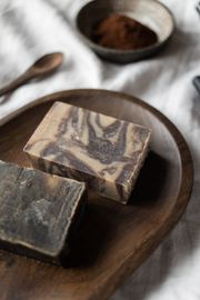 Two pieces of soap are sitting on a wooden plate.