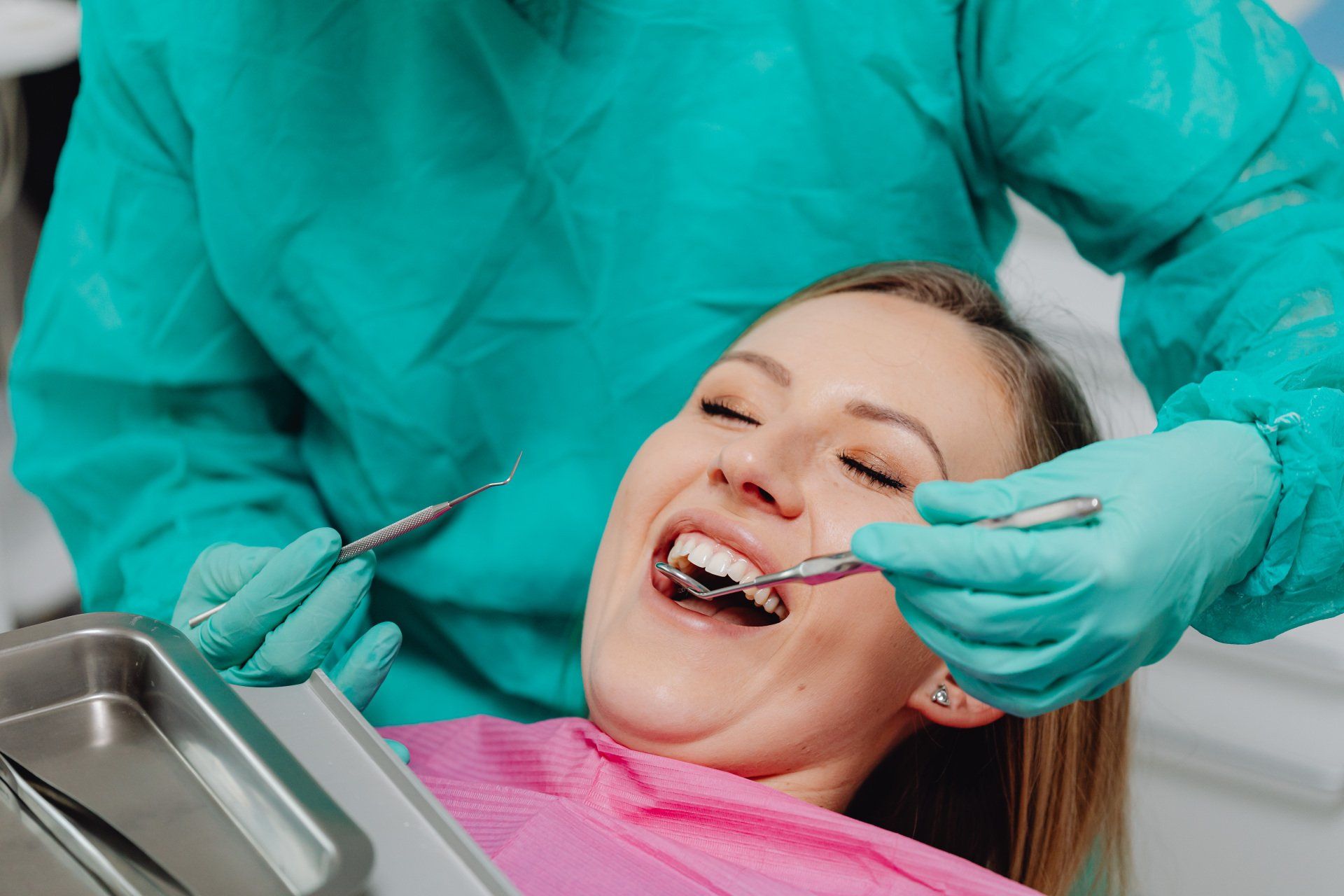 A woman is having her teeth examined by a dentist.