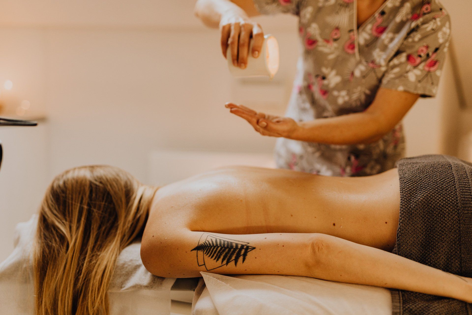 A woman is getting a massage at a spa with candles in the background.