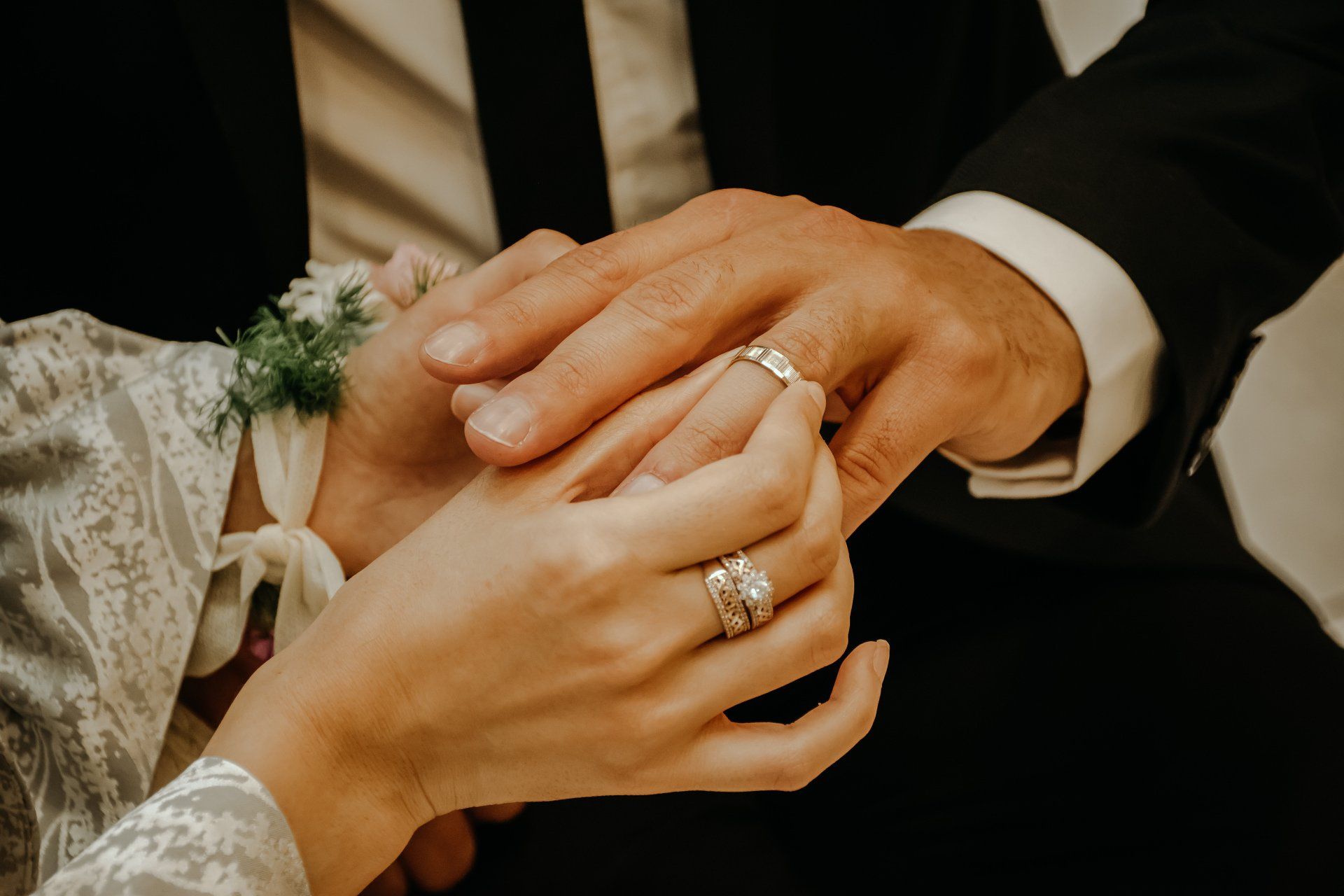 la sposa e lo sposo si tengono per mano con gli anelli