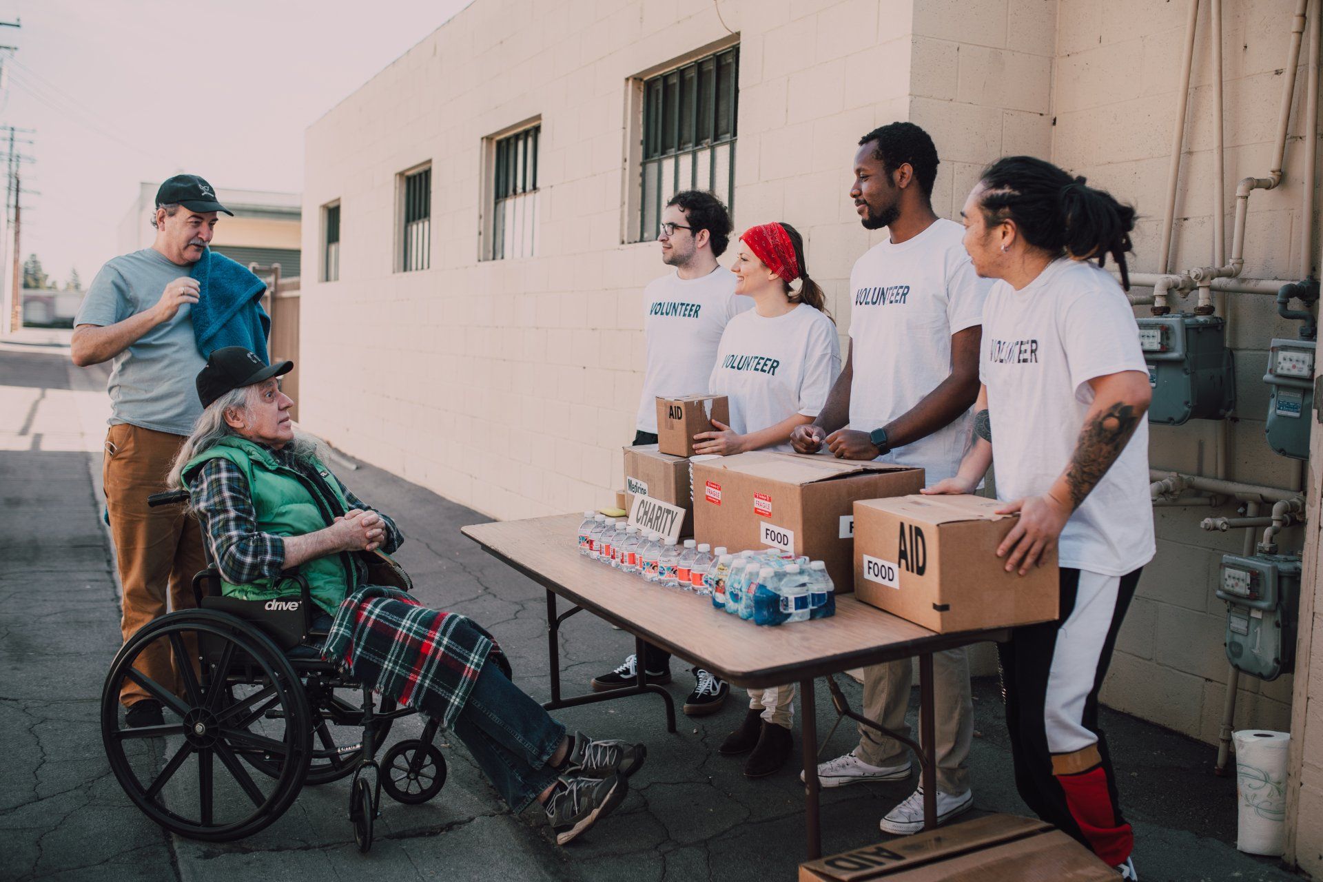 A man in a wheelchair is sitting at a table with volunteers.