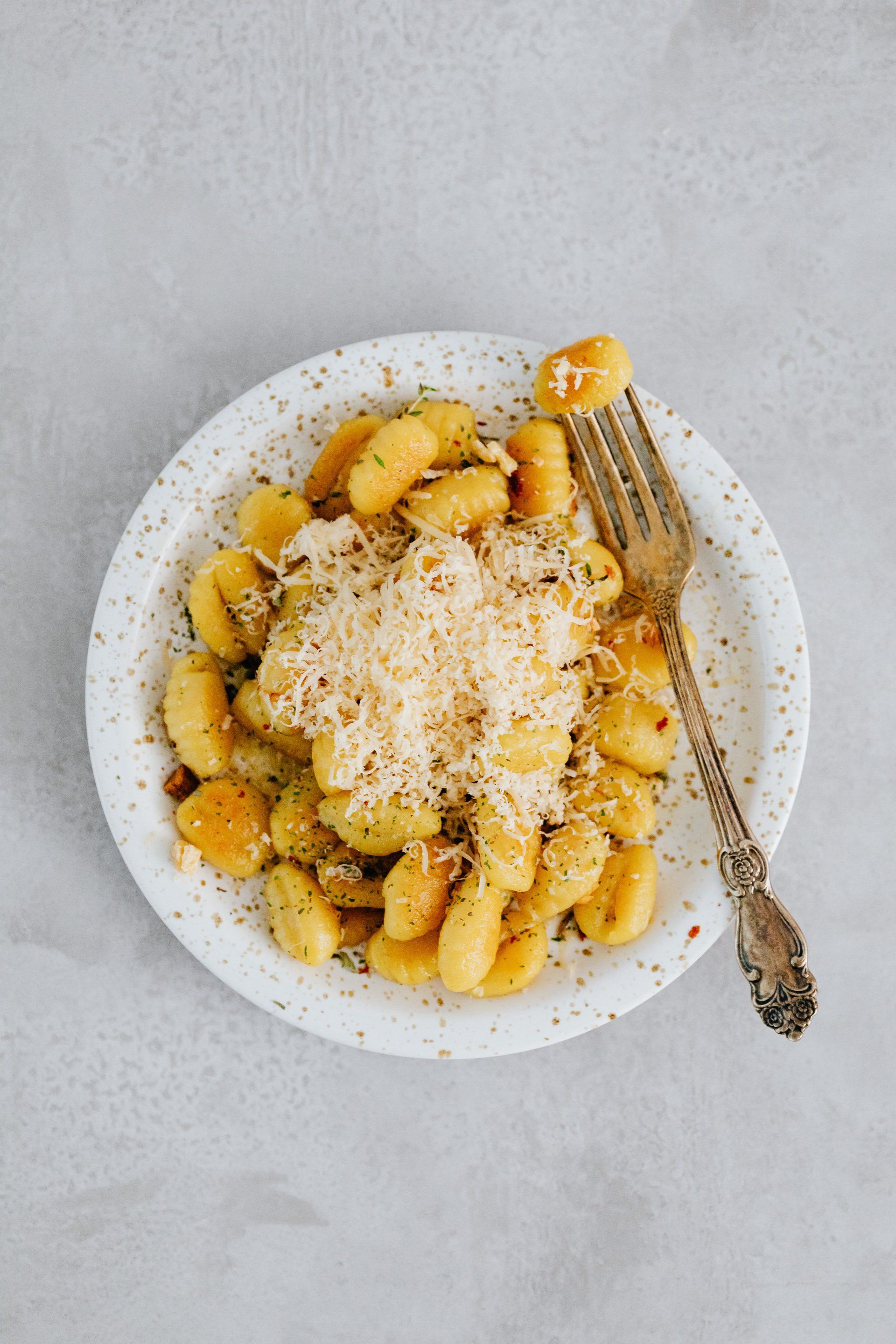 a plate of gnocchi with cheese and a fork