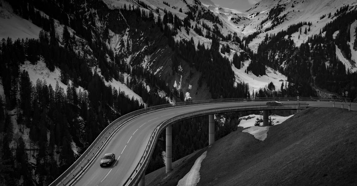 Chalet Escapade A black and white photo of a car driving down a highway in the mountains.
